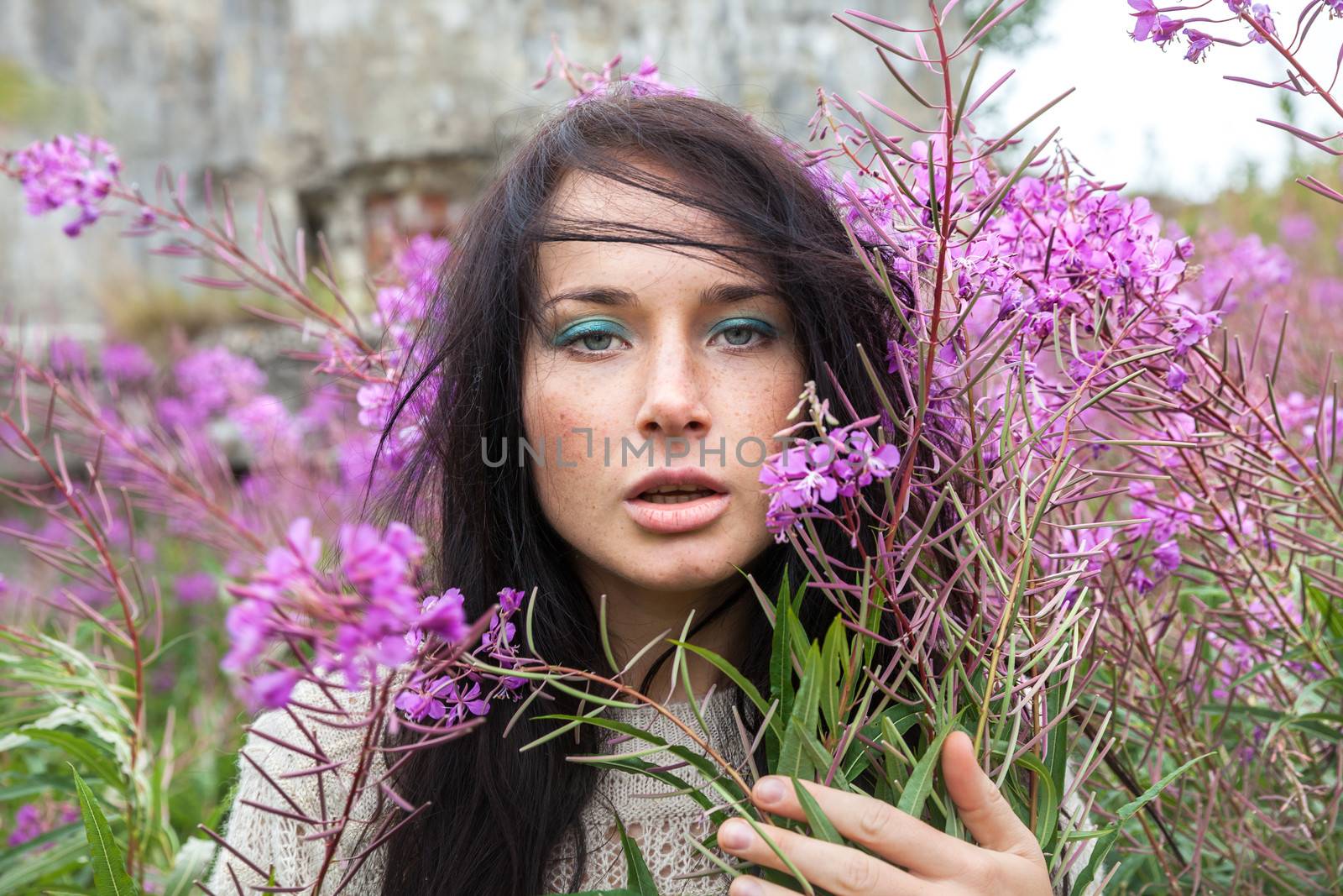 Portrait of beautiful freckled girl among the flowers.