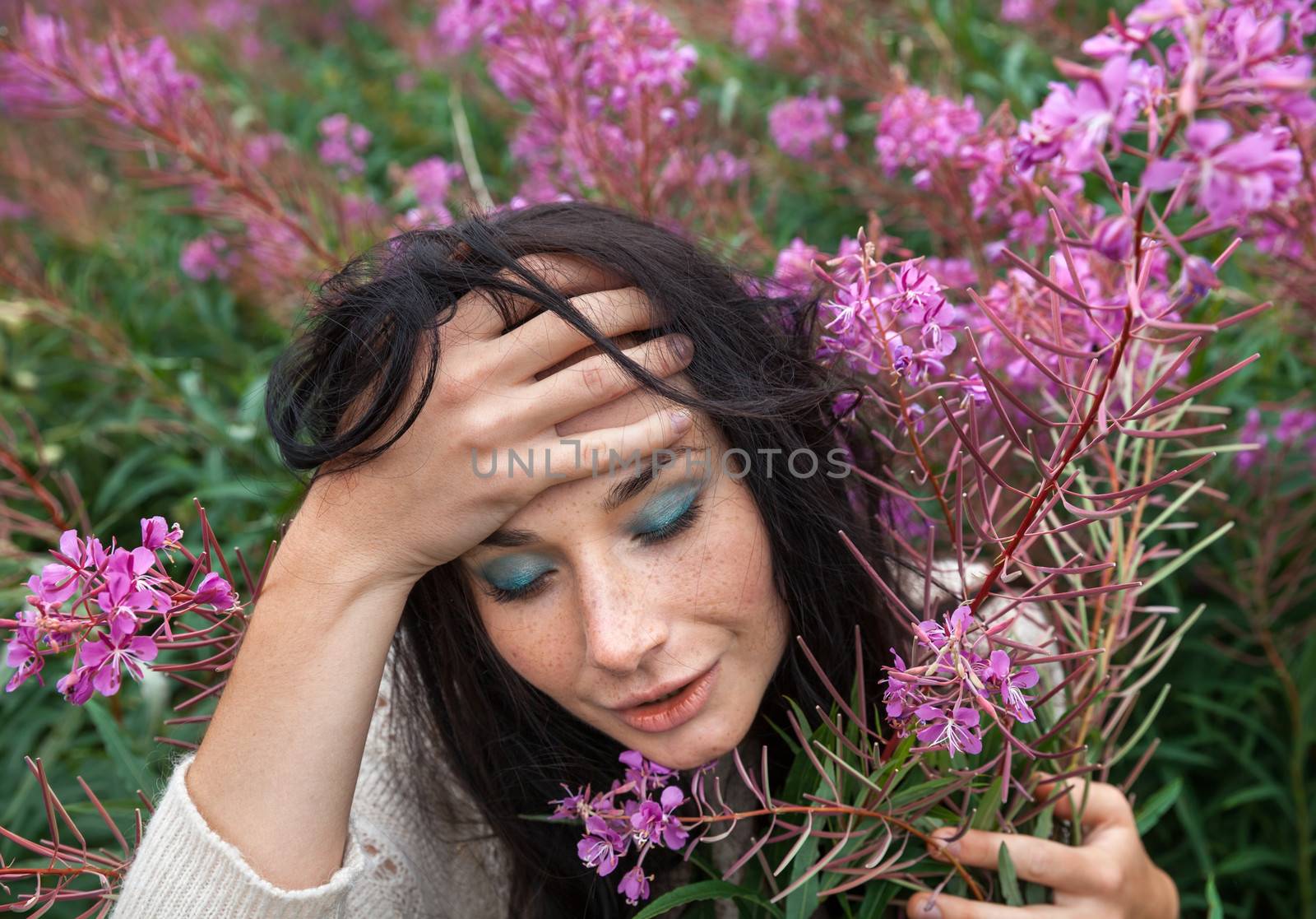 Portrait of beautiful freckled girl among the flowers.