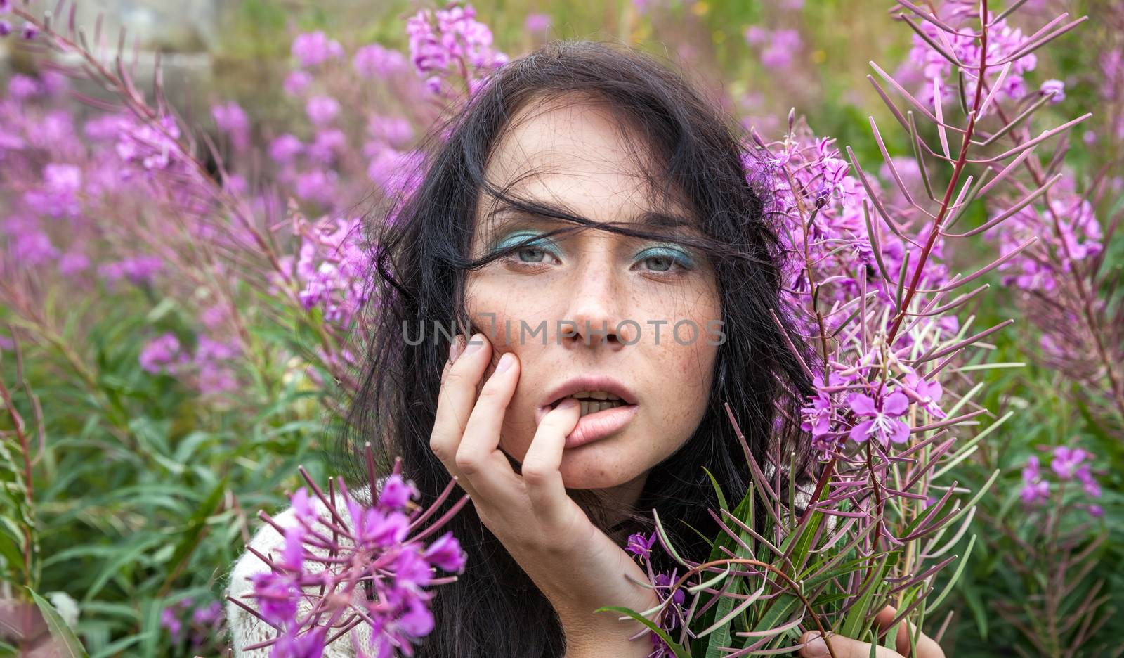 Portrait of beautiful freckled girl among the flowers.