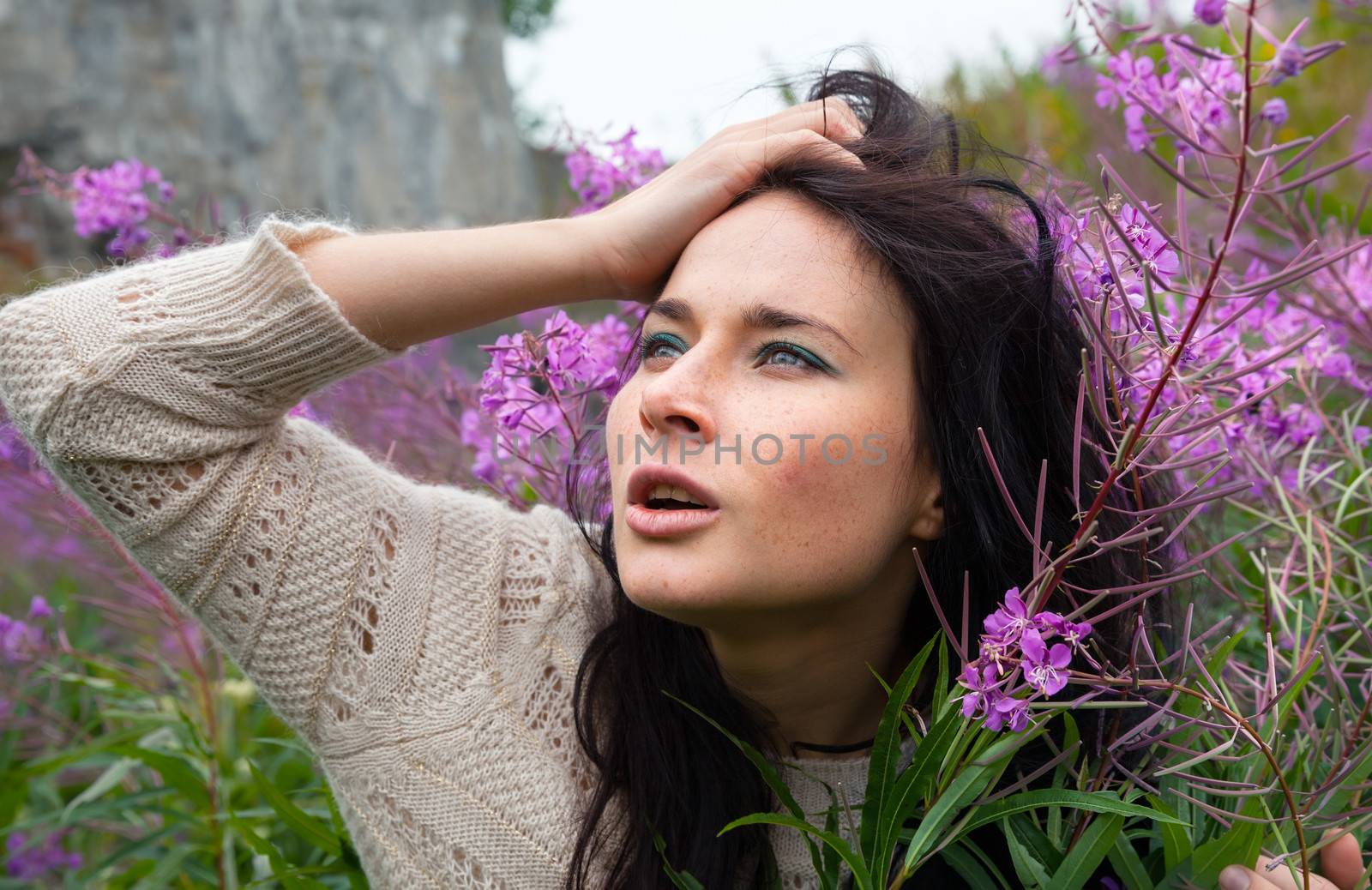 Portrait of beautiful freckled girl among the flowers.