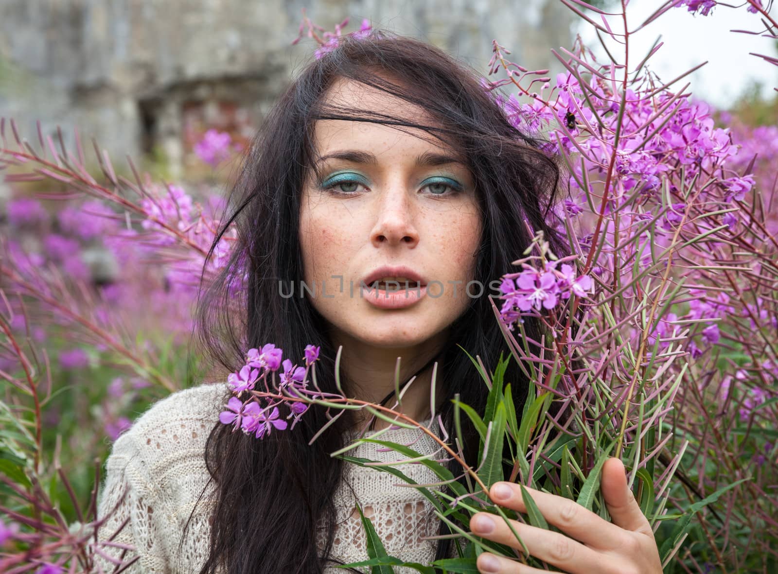 Portrait of beautiful freckled girl among the flowers.