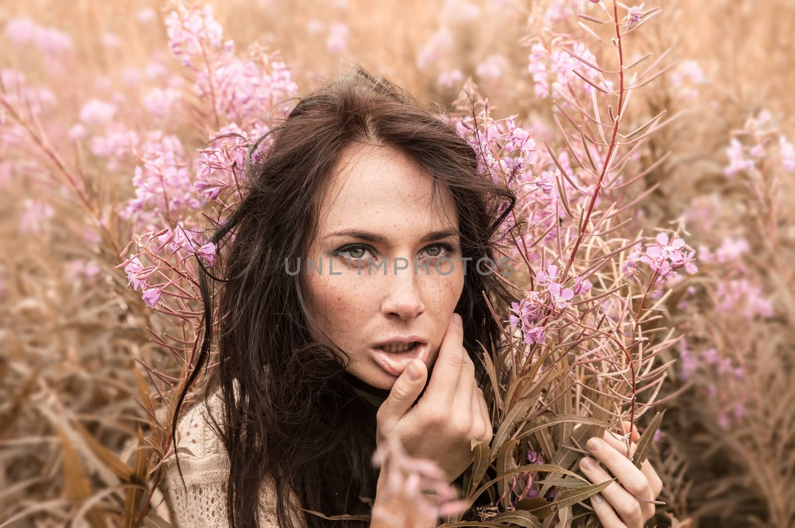 Portrait of beautiful freckled girl among the flowers. Intentional color shift
