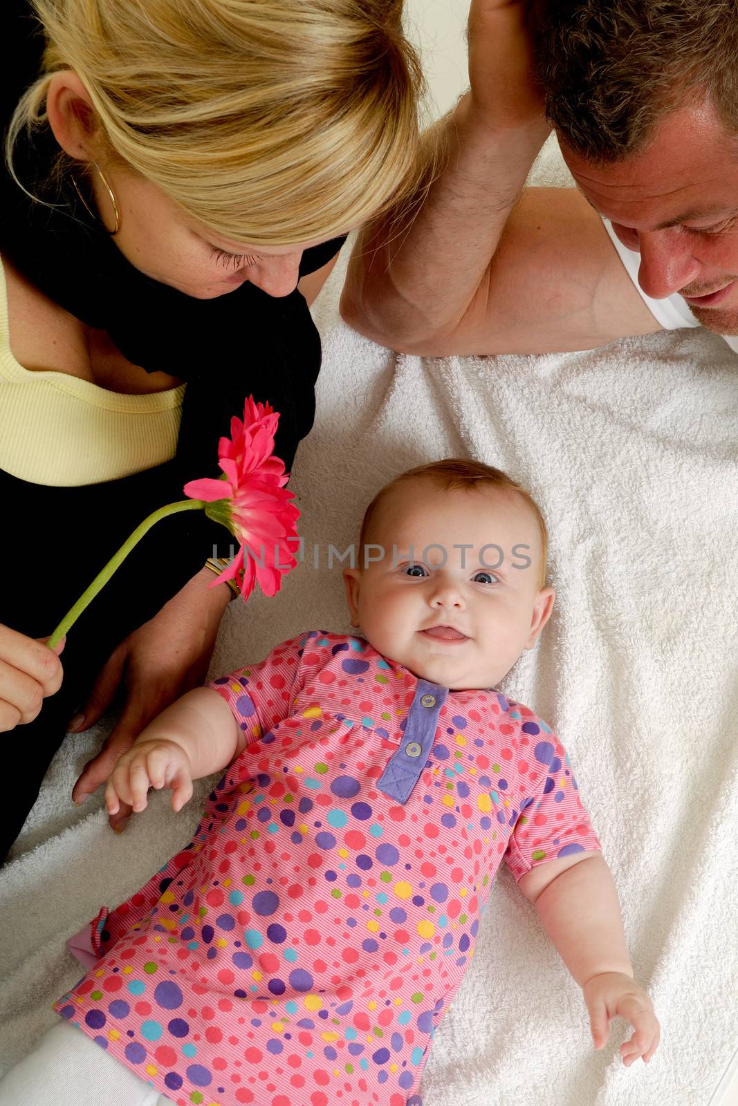 Mother and father are looking at their sweet smiling 4 month old baby.