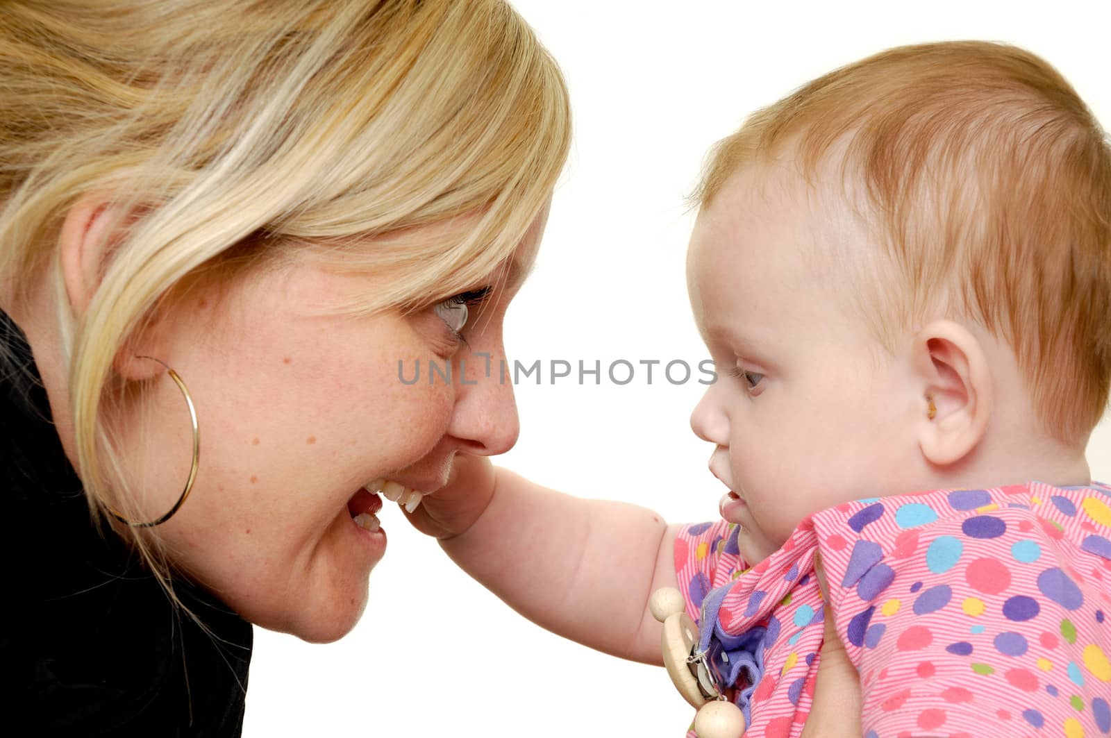 Mother is looking down on her sweet smiling baby. Taken on a white background.