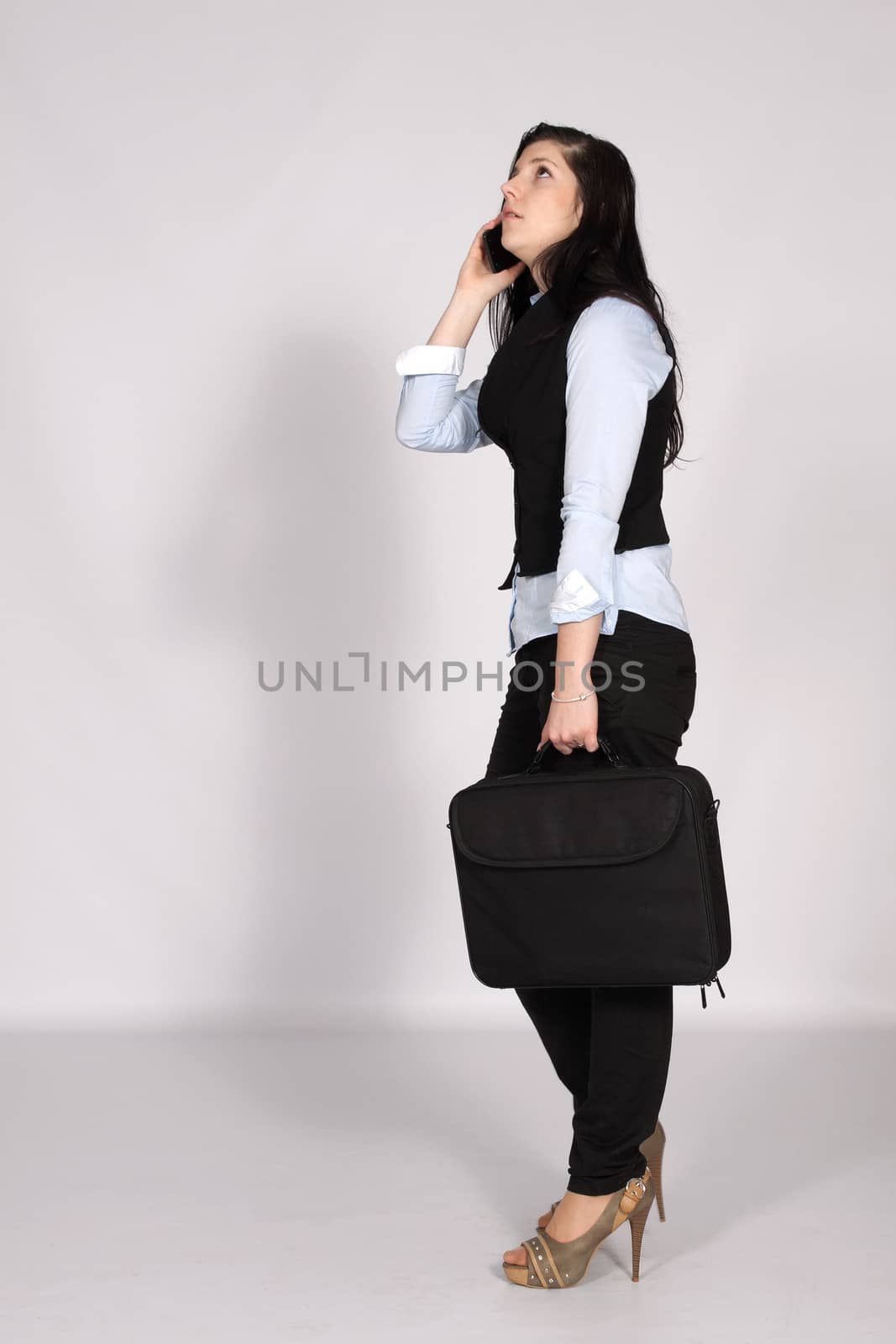 Young woman standing with laptop bag and phone