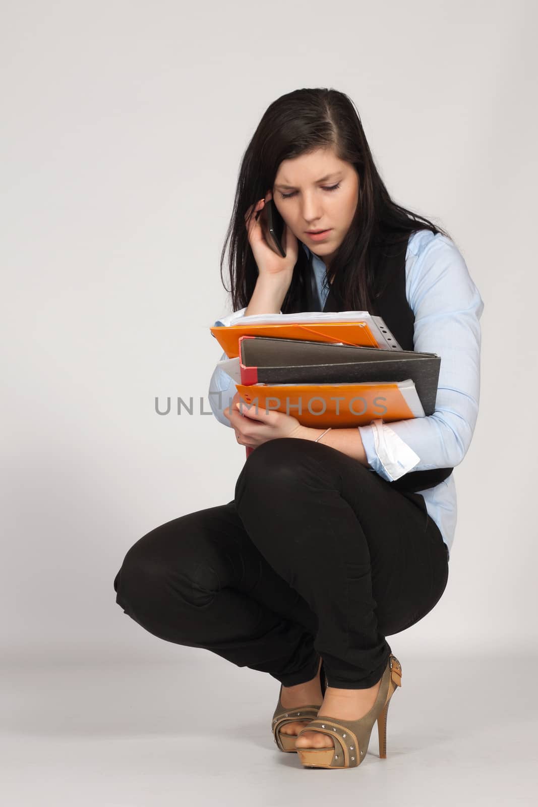 Young woman is squatting and phone and viewing documents in his hands