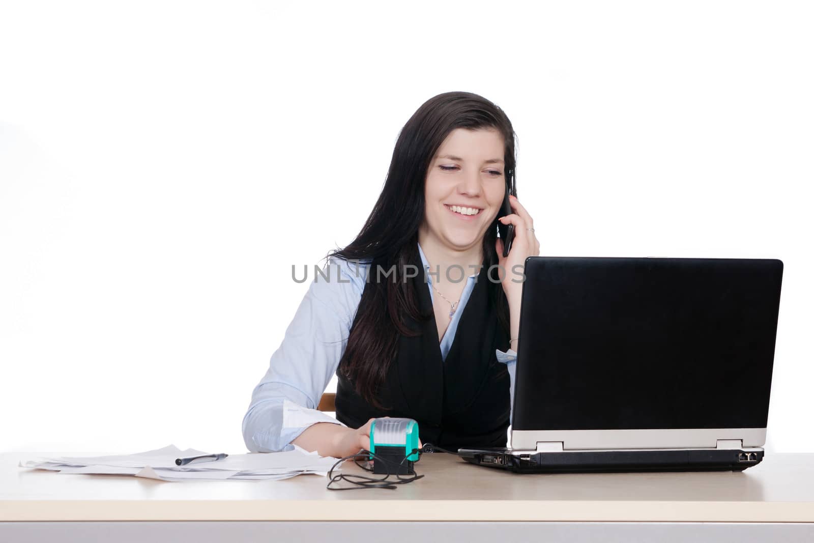 Young woman behind a desk phone and working at laptop, isolated on white background