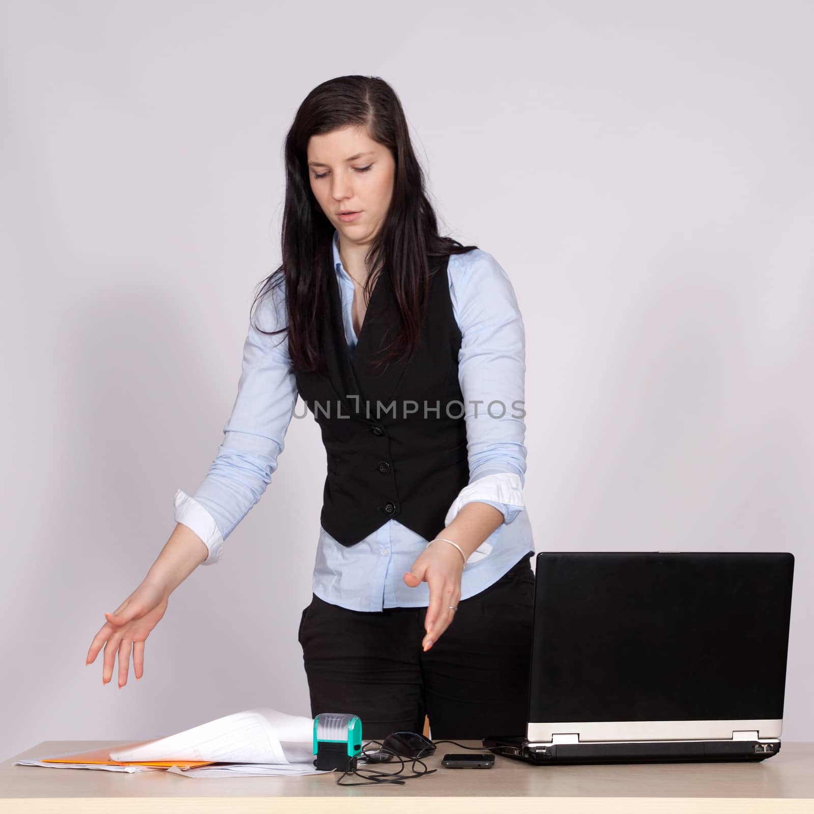 Young female boss at table with laptop throwing papers on the table, and upsets