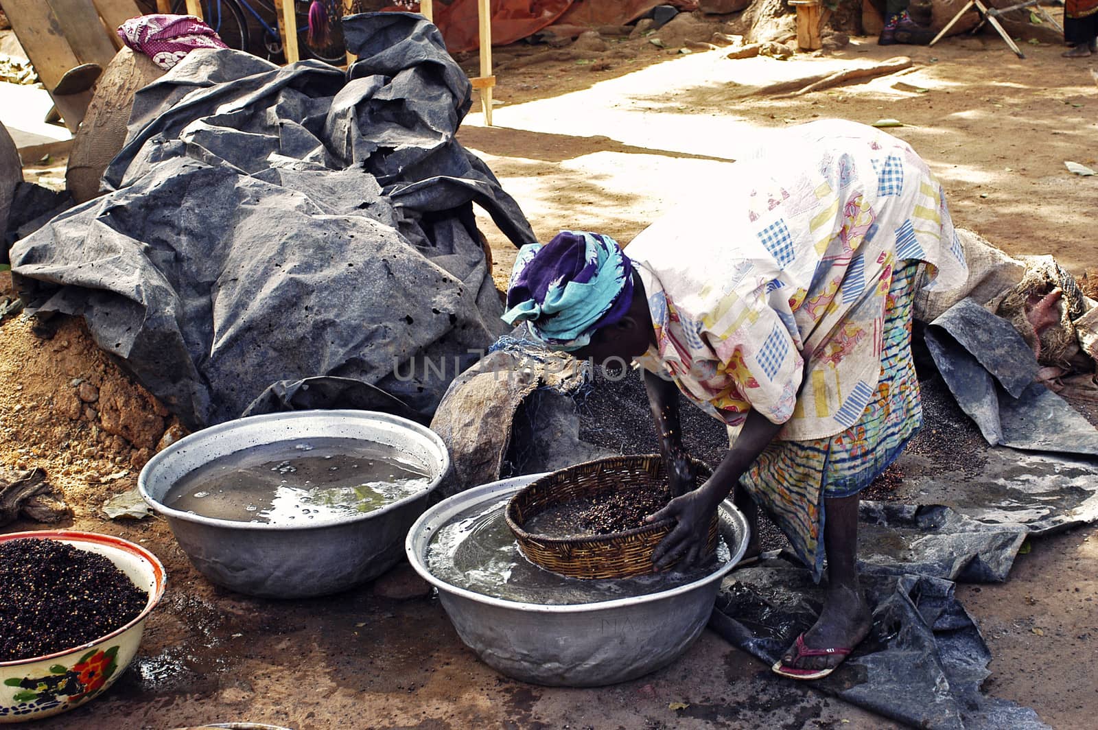 an old woman cooking local beer made from millet in Burkina Faso called Dolo in the middle of a street in Bobo-Dioulasso