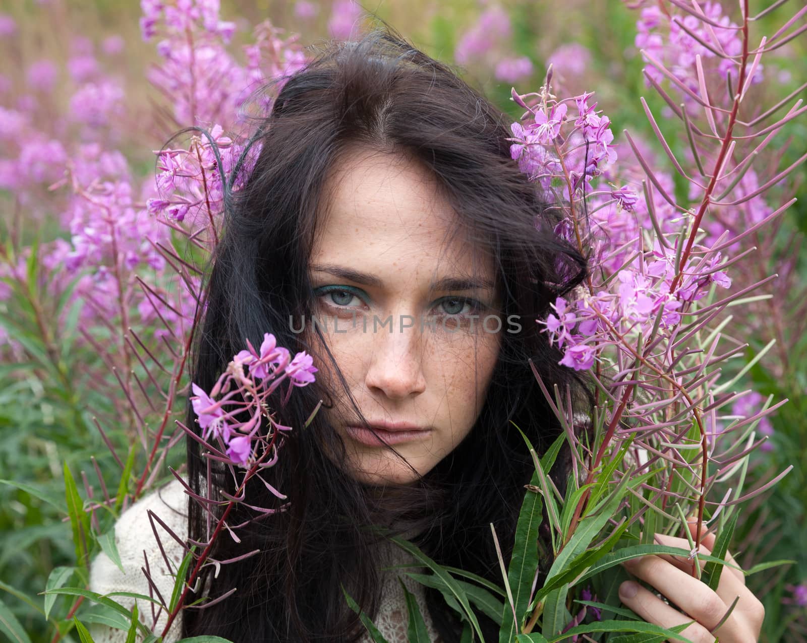 Portrait of beautiful freckled girl among the flowers.