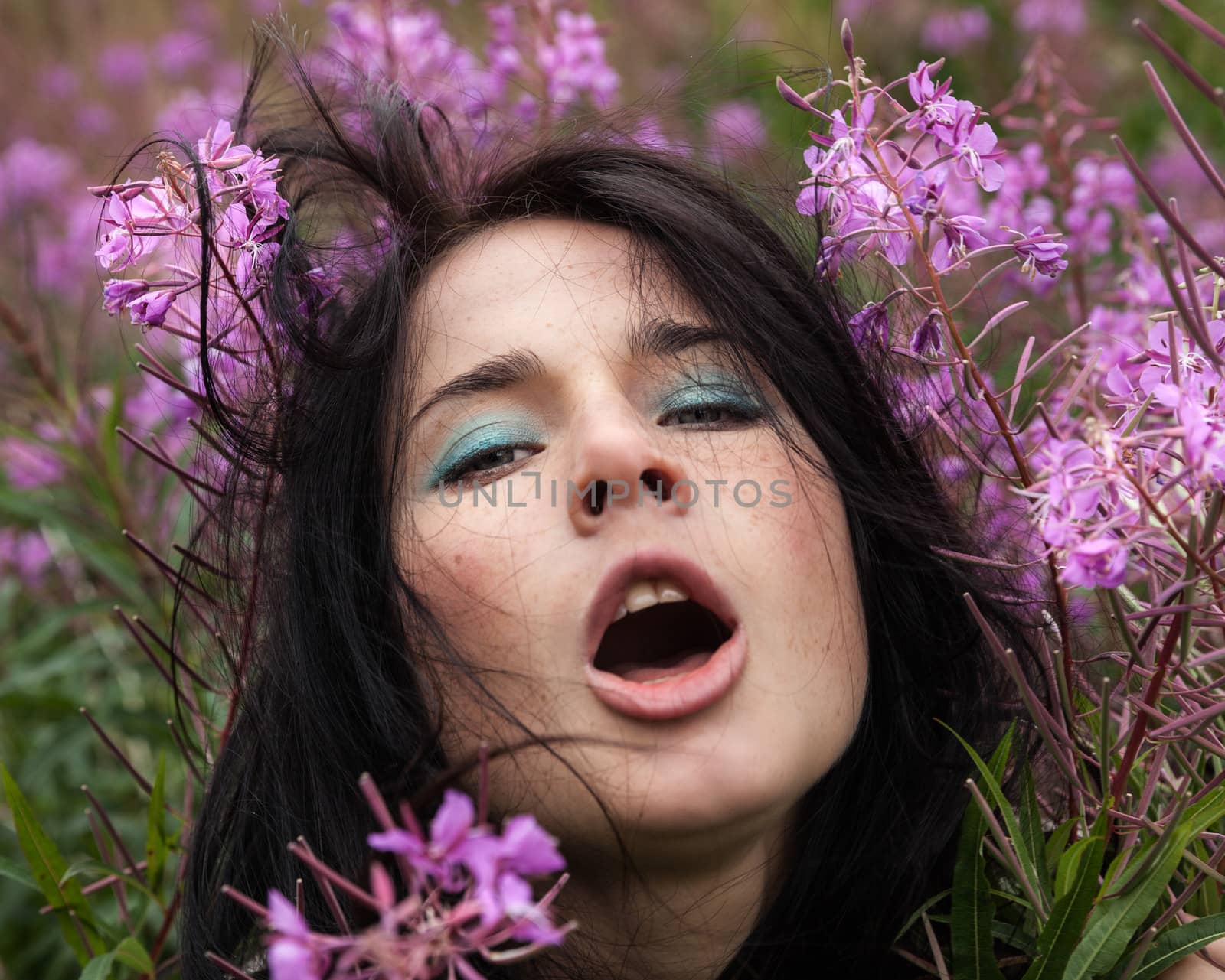 Portrait of beautiful freckled girl among the flowers.