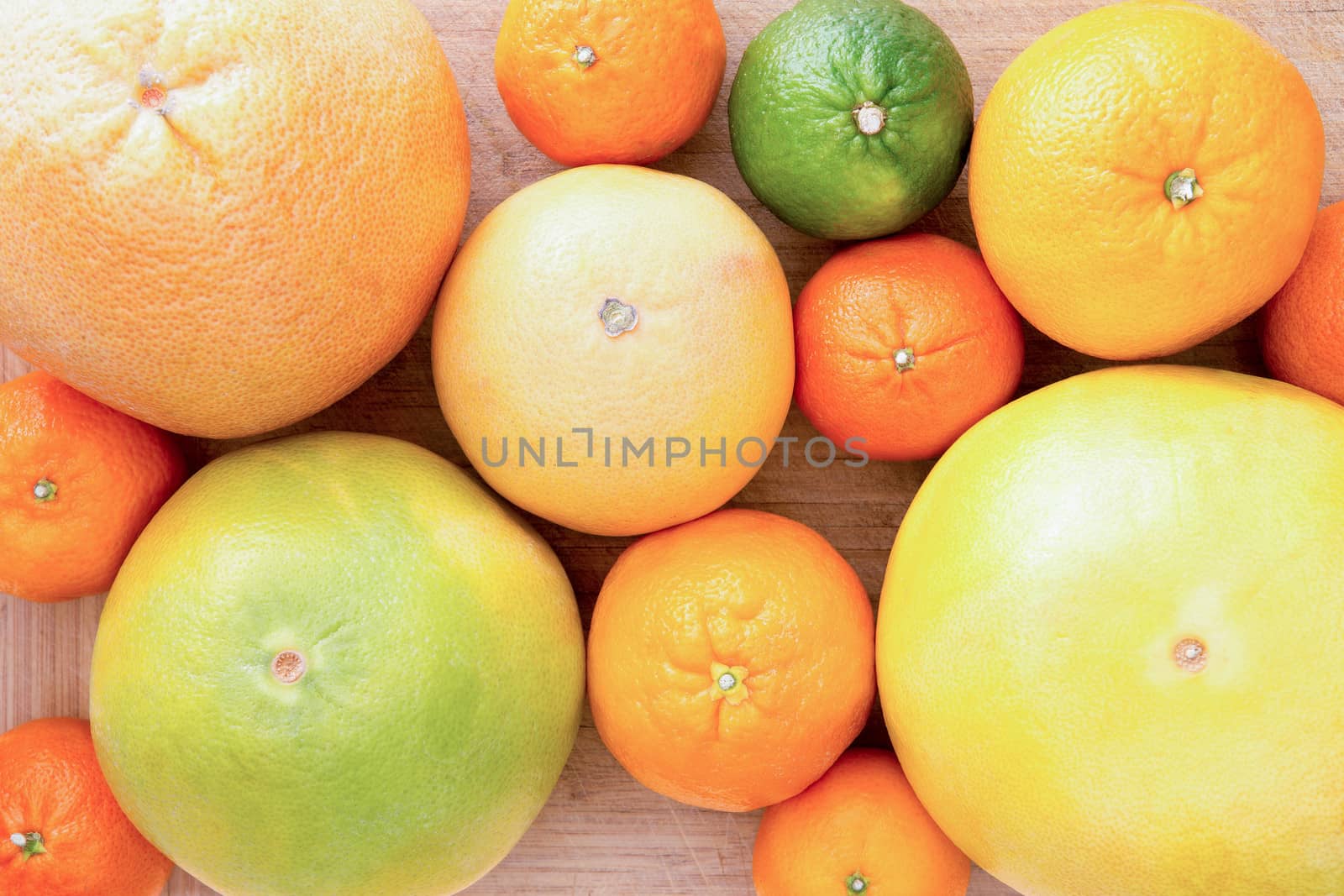 Background of assorted citrus fruit with lemon, lime, orange, tangerine, clementine and grapefruit, close up view from above on a wooden background