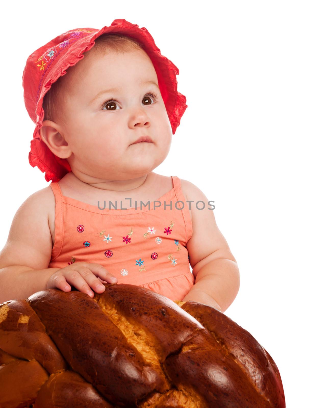 Baby girl in a pink hat holding bread. Isolated on white