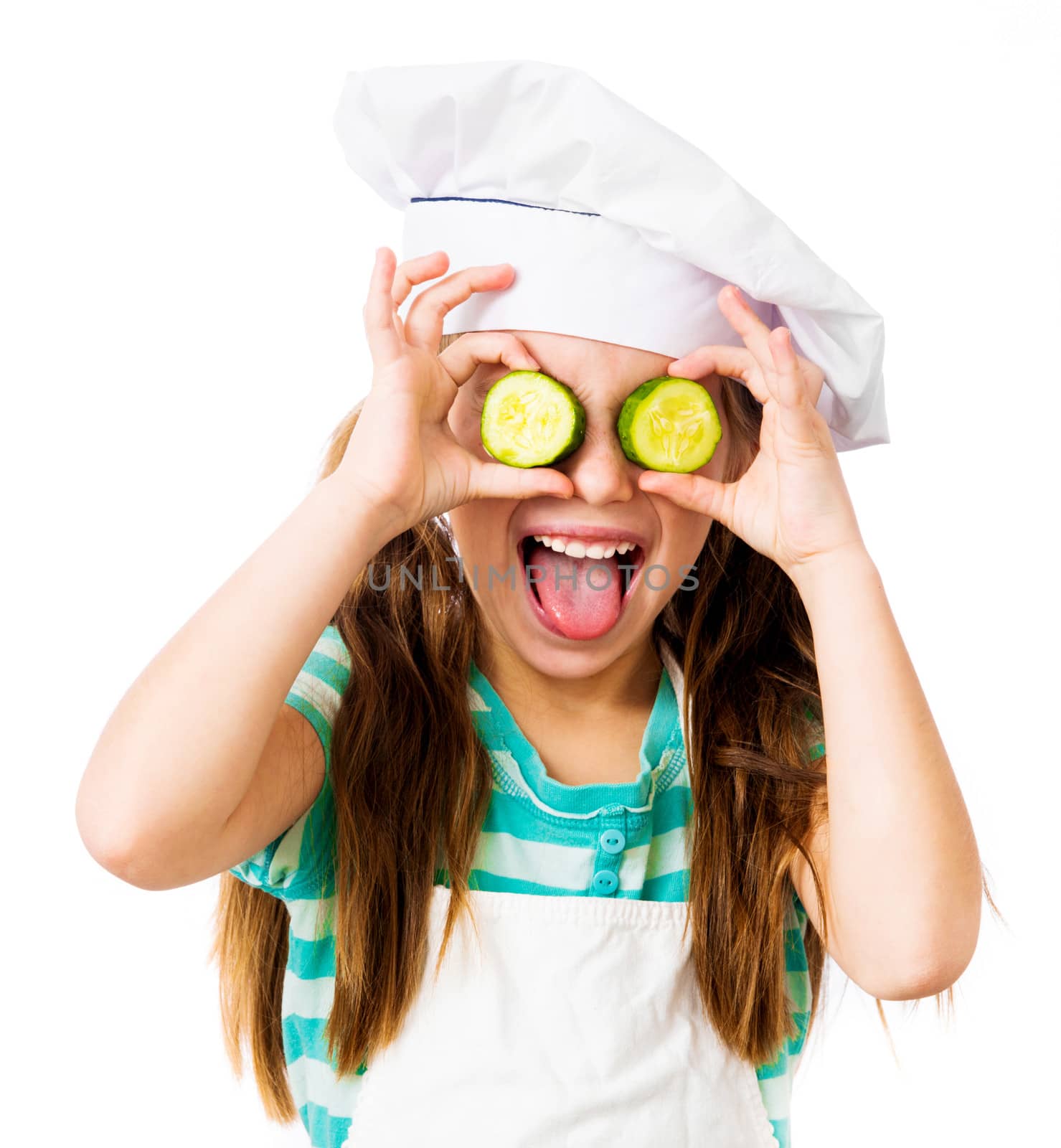 little girl in chef hat with cucumber slices on the eyes shows tongue on a white background