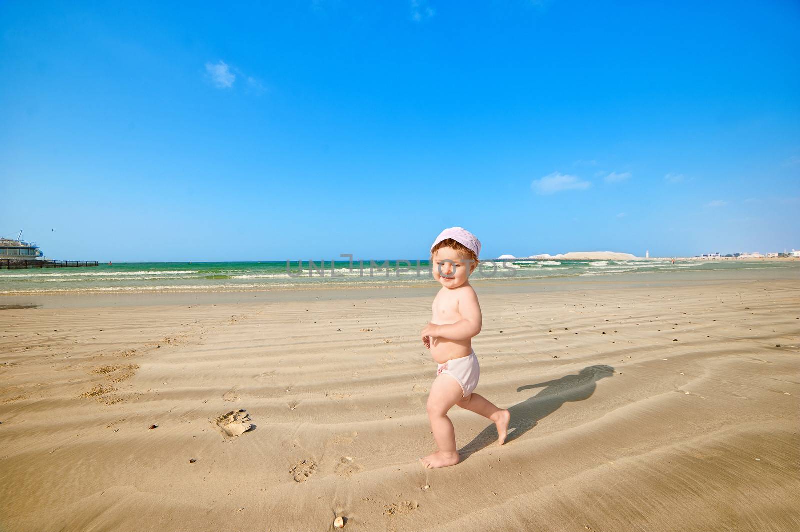 A little girl goes through the sand on the beach