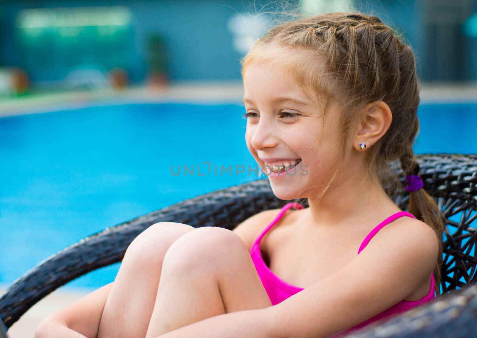 little cute girl holding hands up near a swimming pool