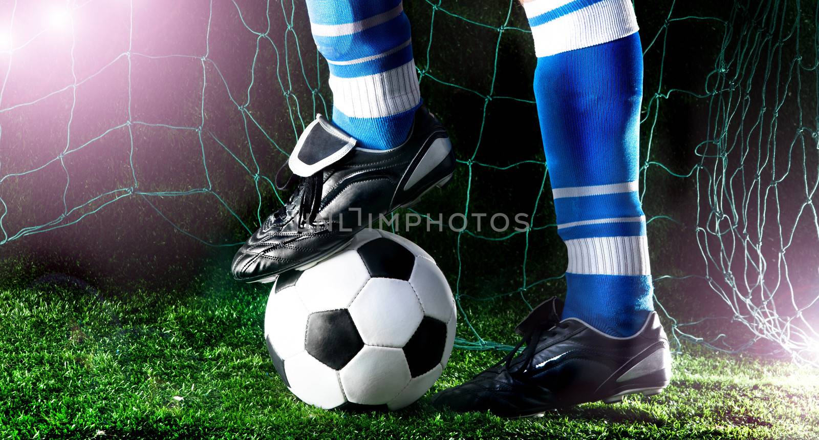 Soccer player's feet in casual pose on playing field with dark background