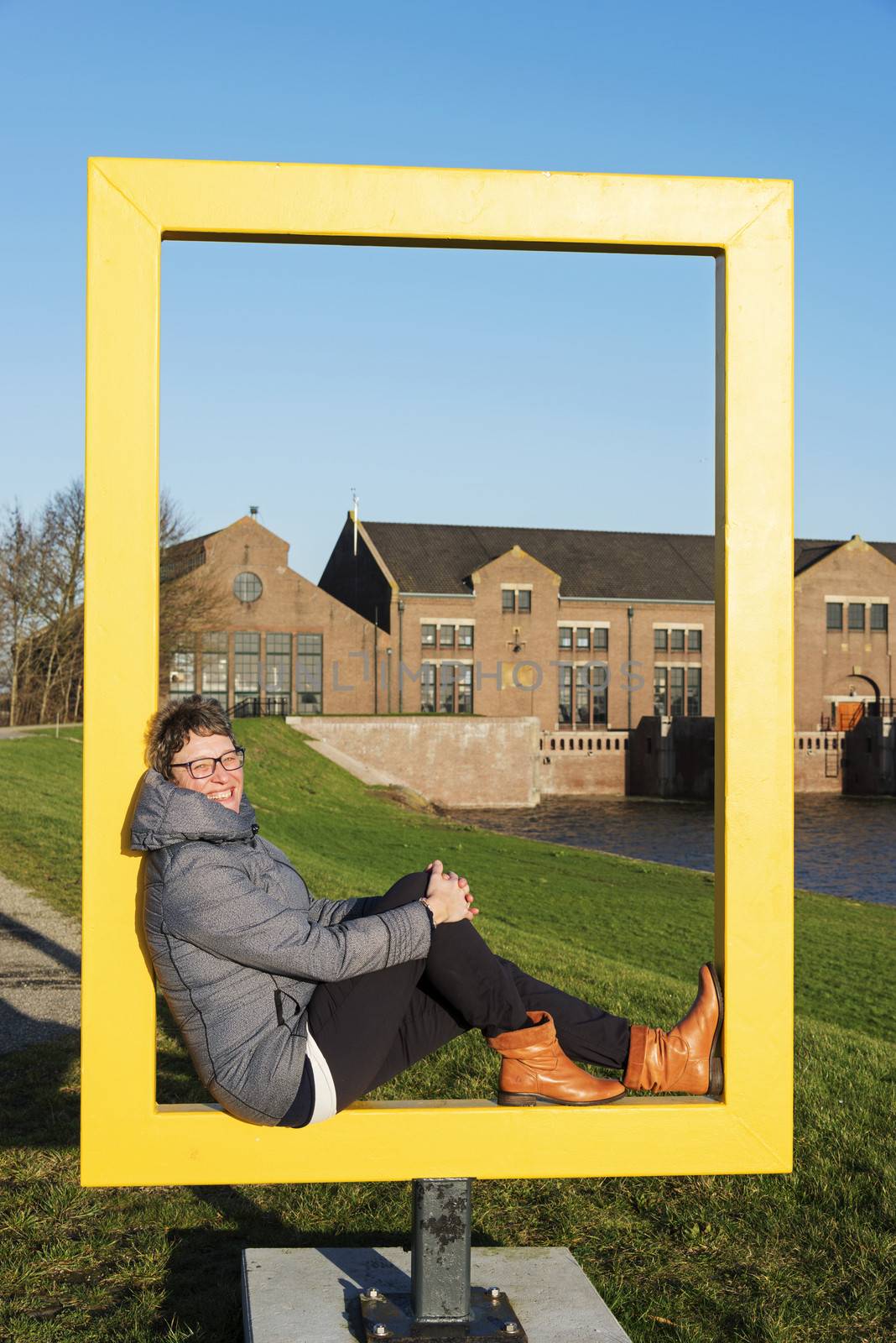 adult causcasian woman in yellow frame with the wouda steamgemaaal as background, the alrgets working steam pump station in the world 