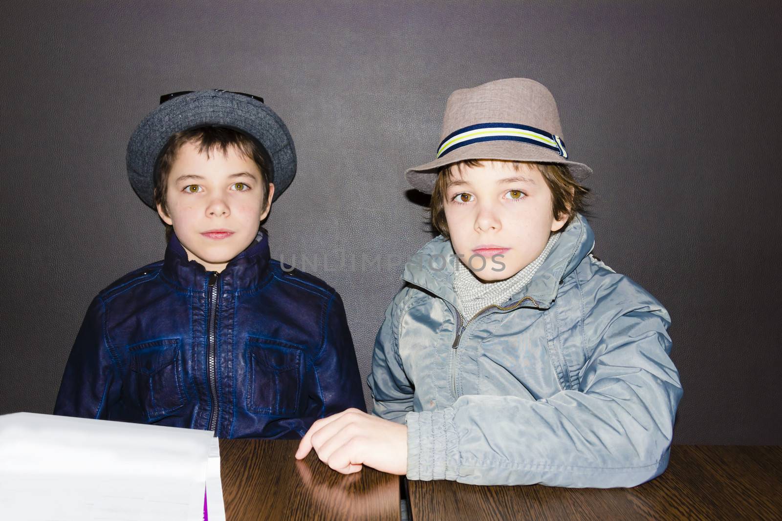 two boys wearing hats at a table in a cafe
