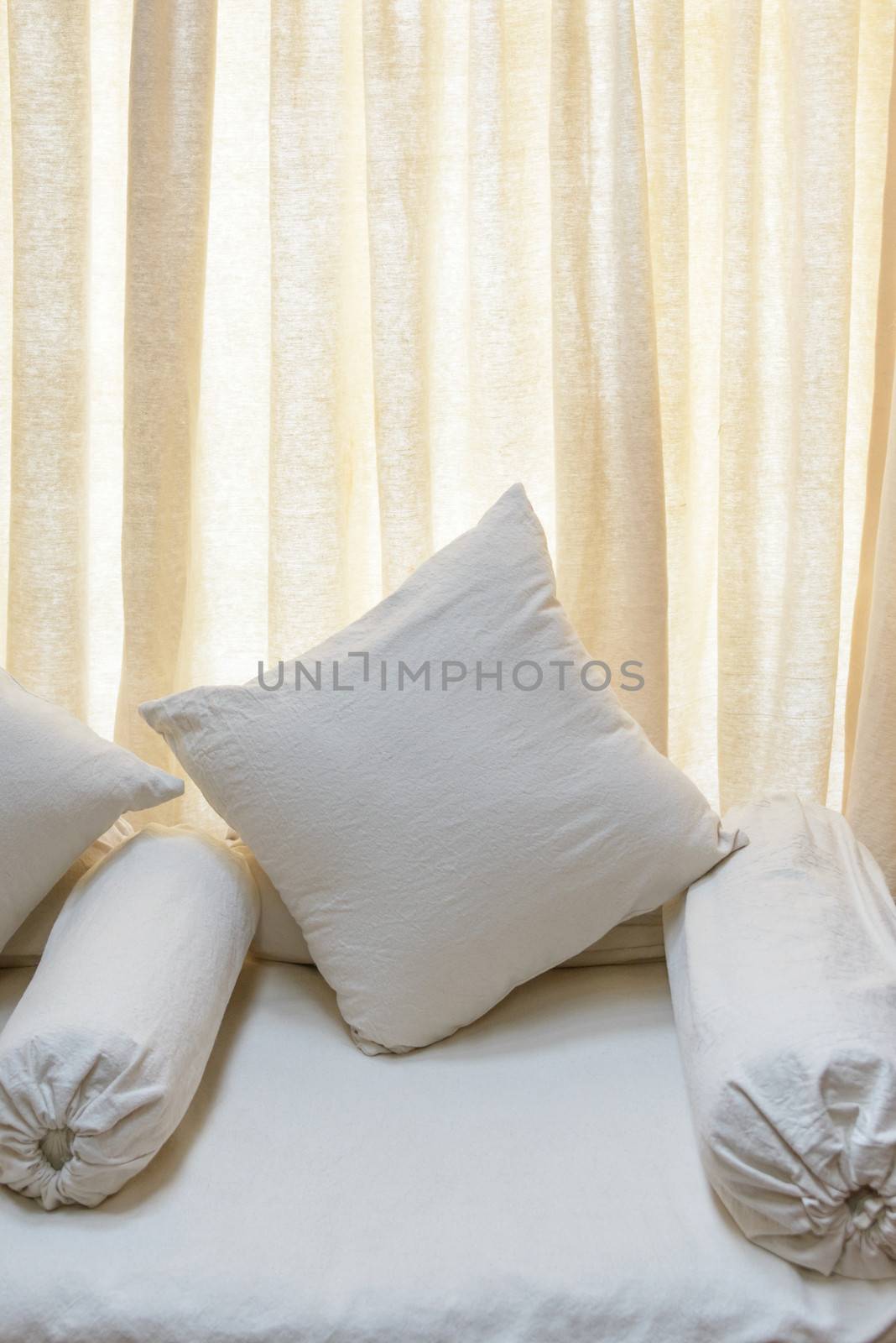 White sofa and cushions, backlit curtain background