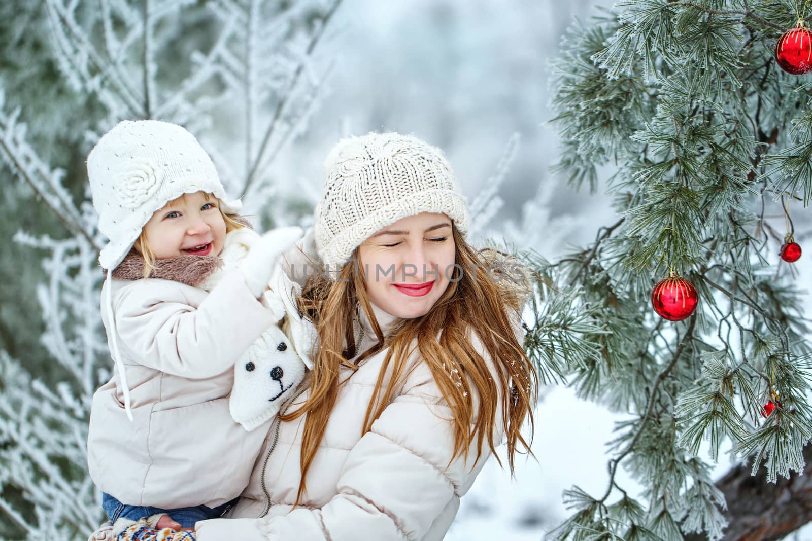 Mother holds daughter on hands in winter forest by Vagengeym