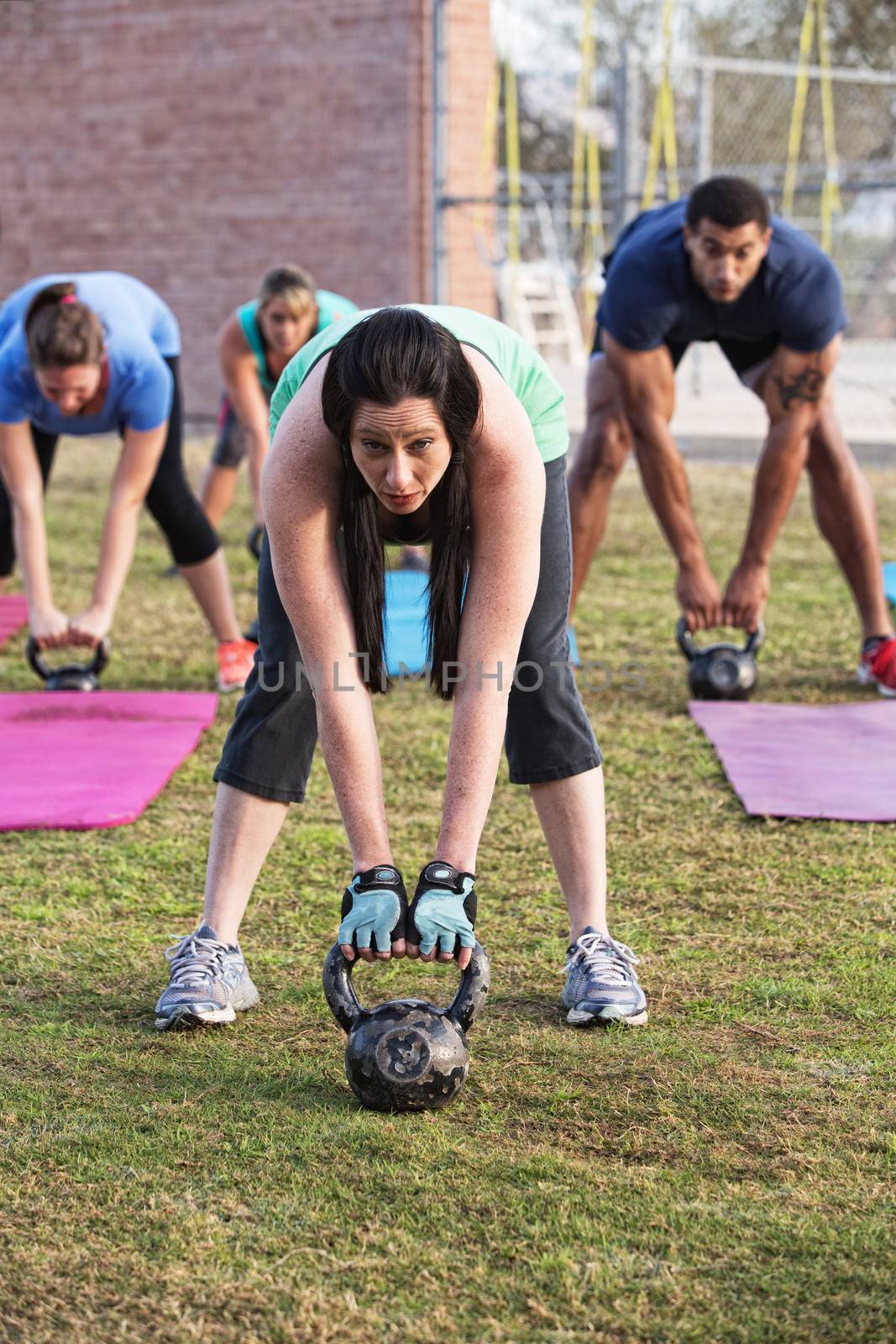 Beautiful woman leading group with kettle bell weights