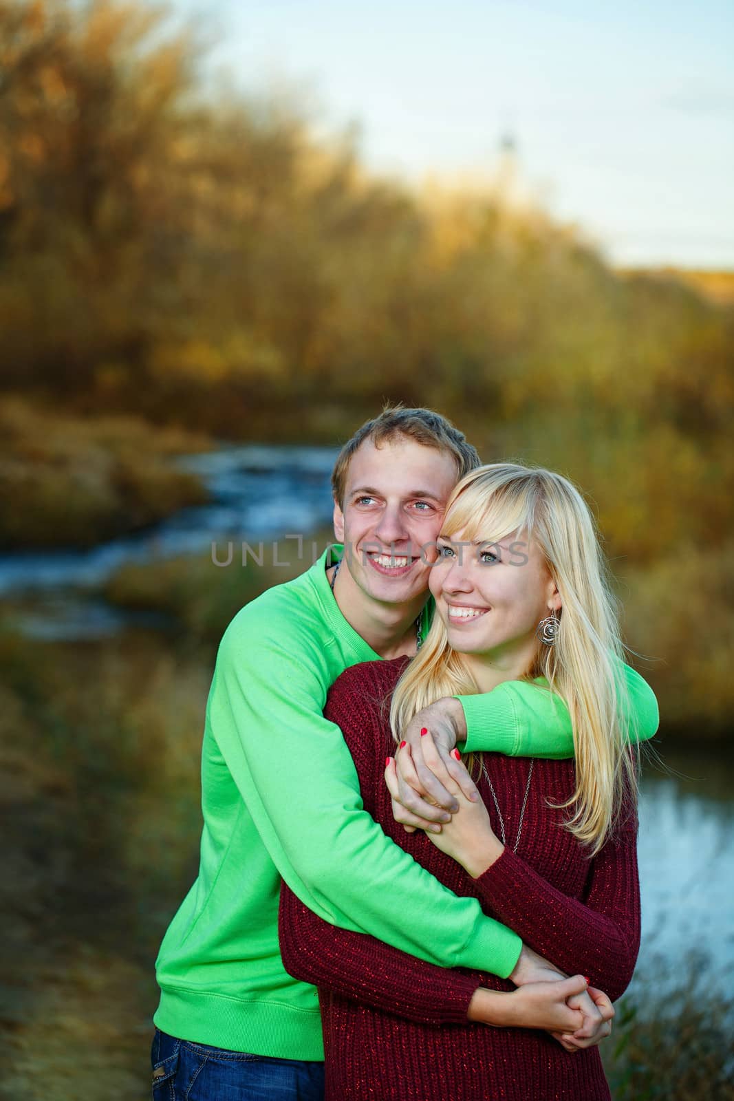 Young couple tenderly and lovingly embrace each other on banks of river