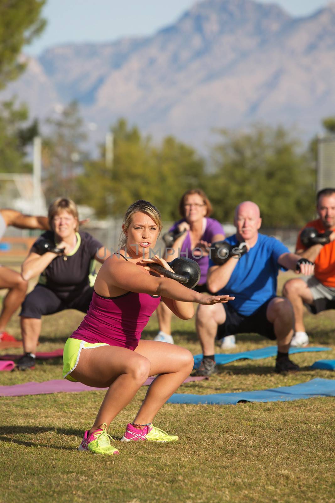 Mixed group of adults training with weights outdoors