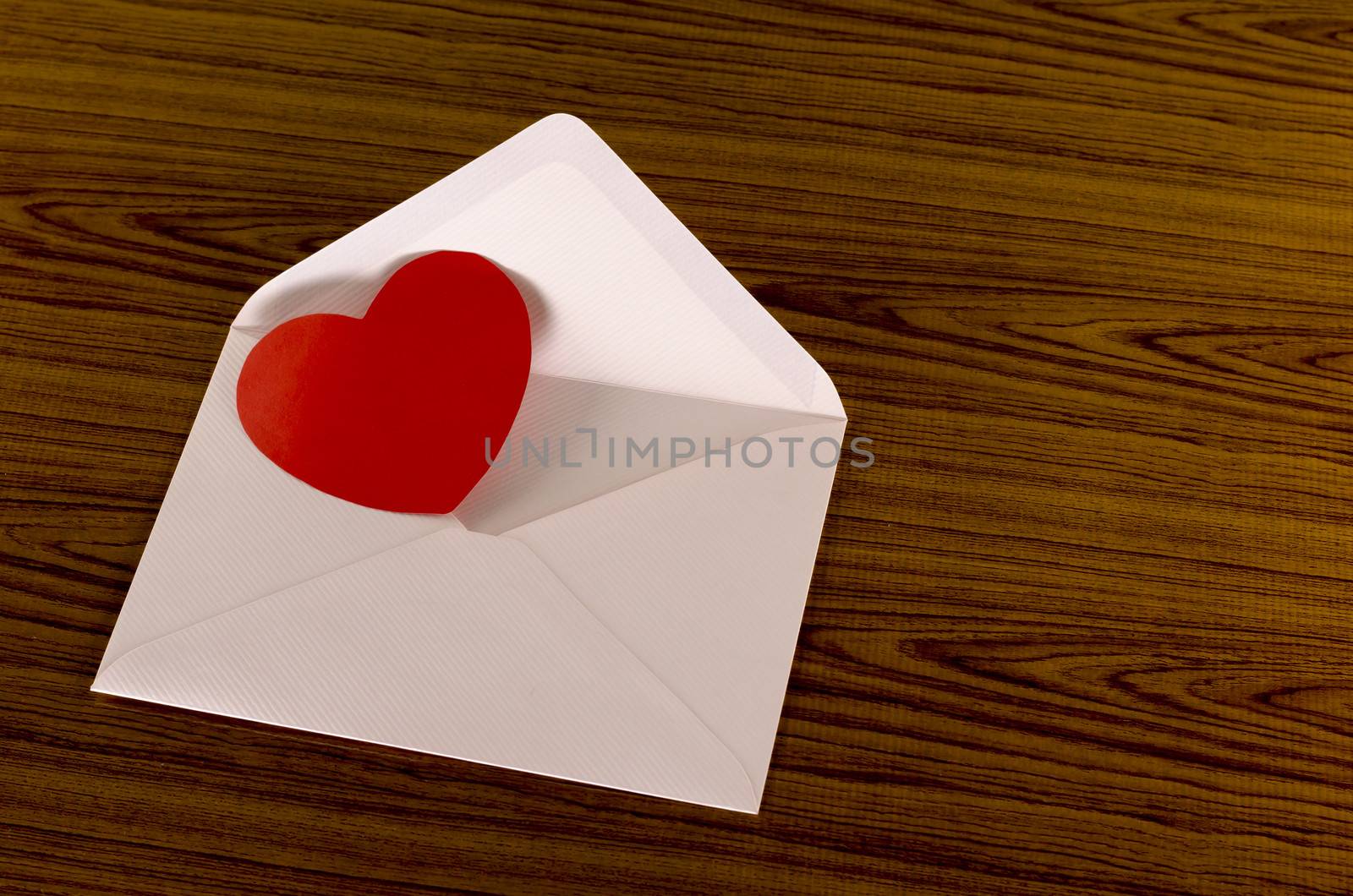 red heart with pink envelope on wooden background