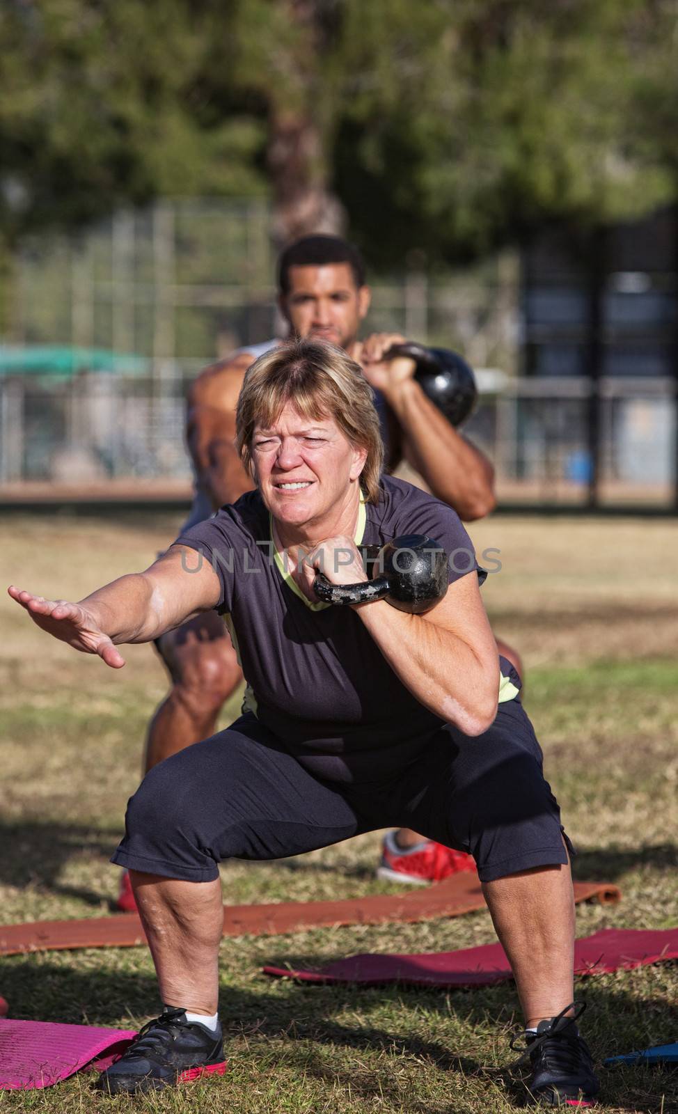 Strong middle aged woman squatting with kettle bell weights