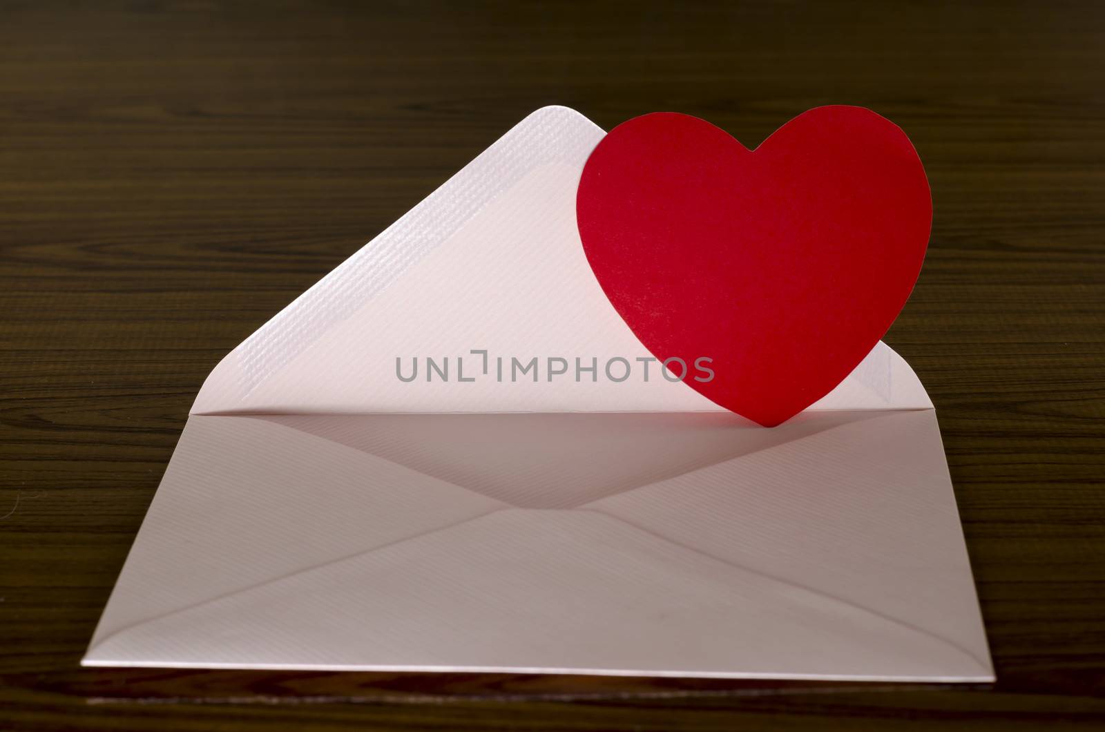 red heart with pink envelope on wooden background