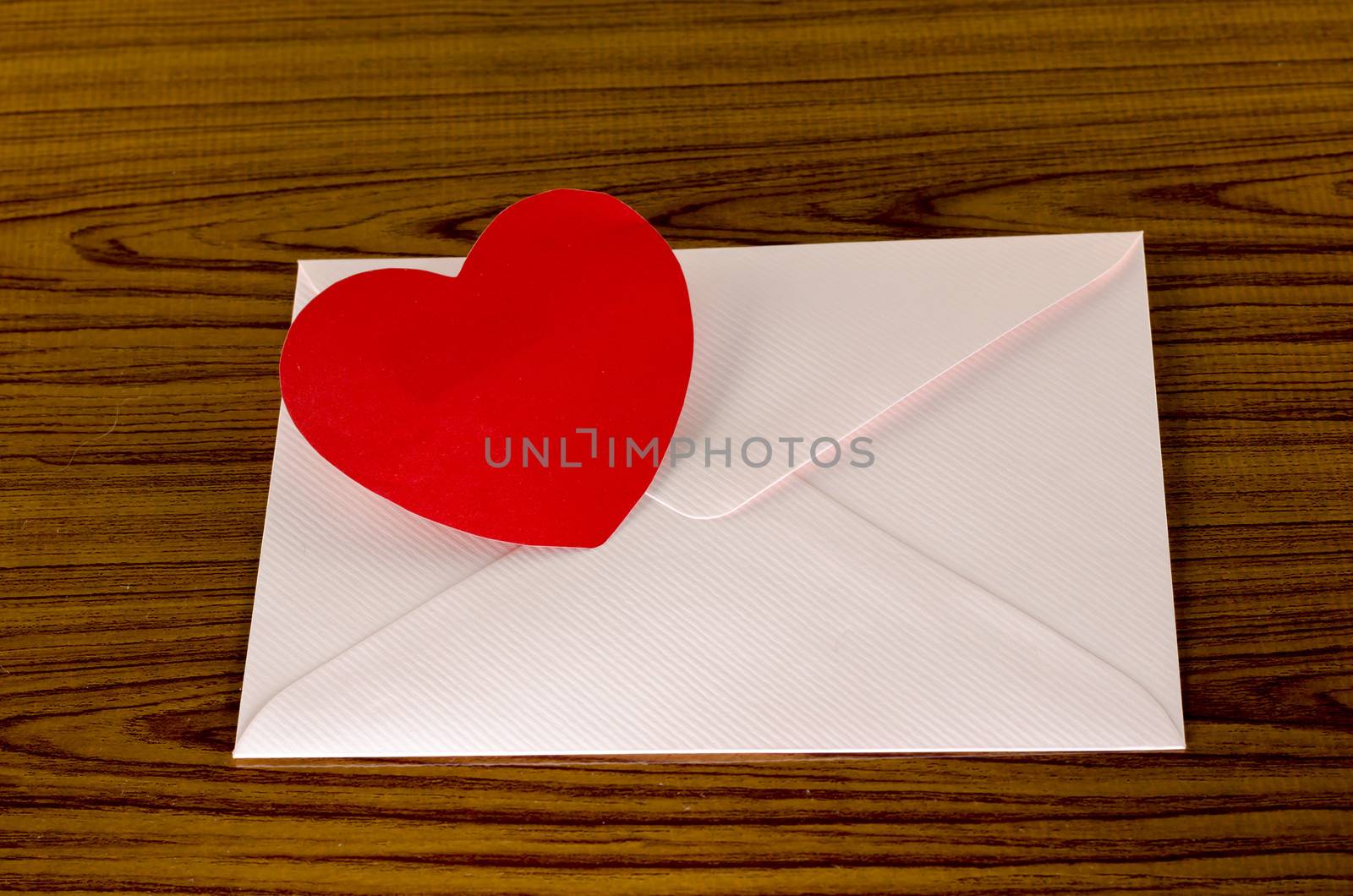 red heart with pink envelope on wooden background