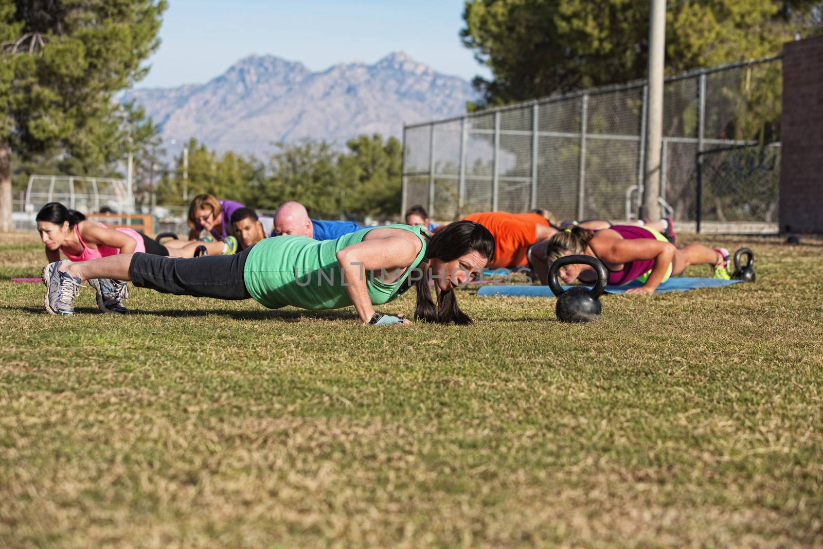 Boot camp fitness group doing push up exercises outdoors