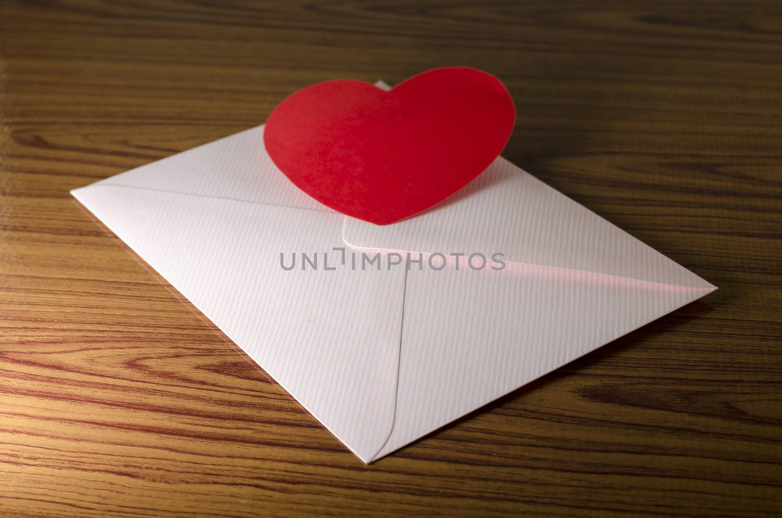 red heart with pink envelope on wooden background