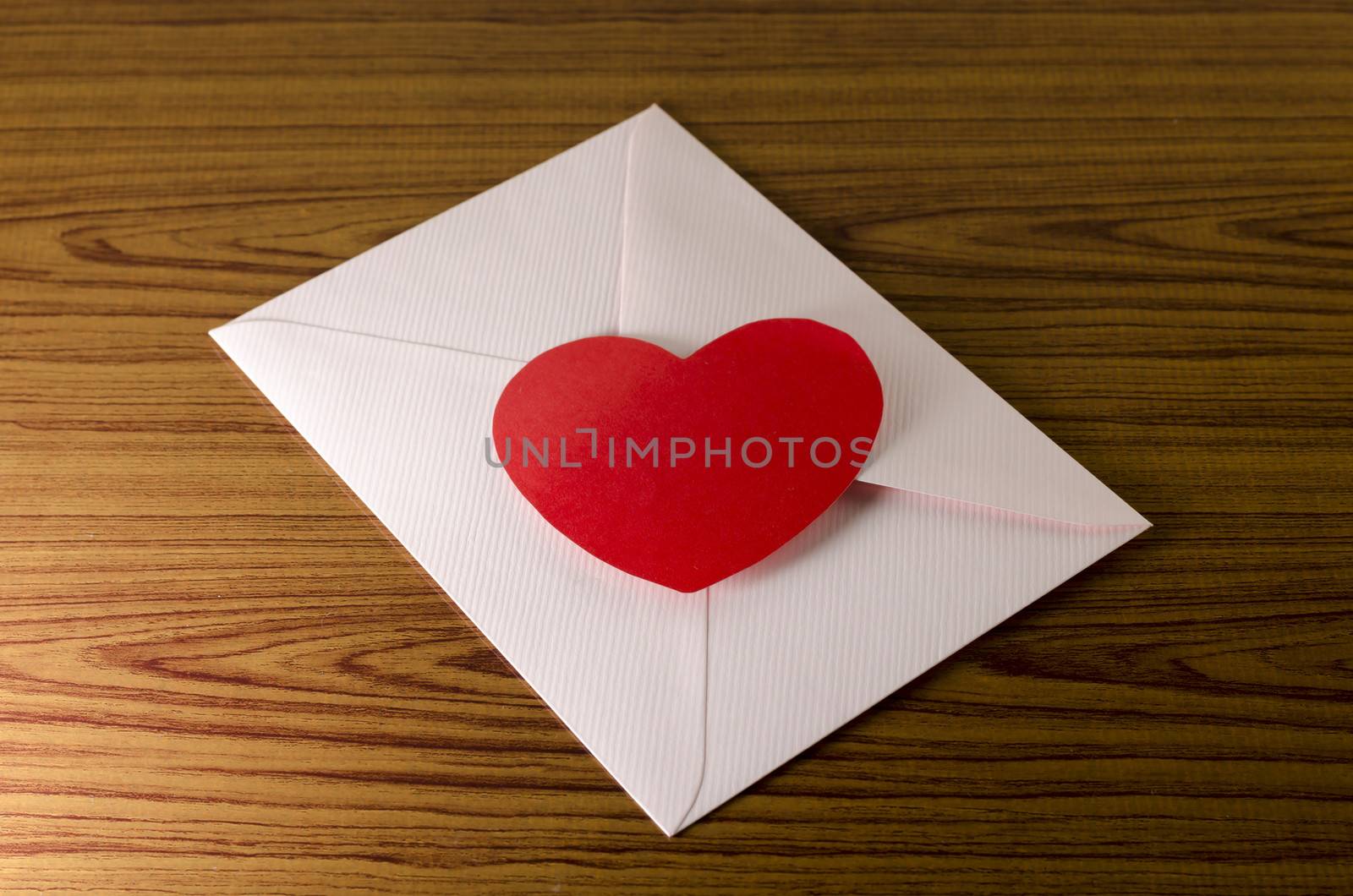 red heart with pink envelope on wooden background