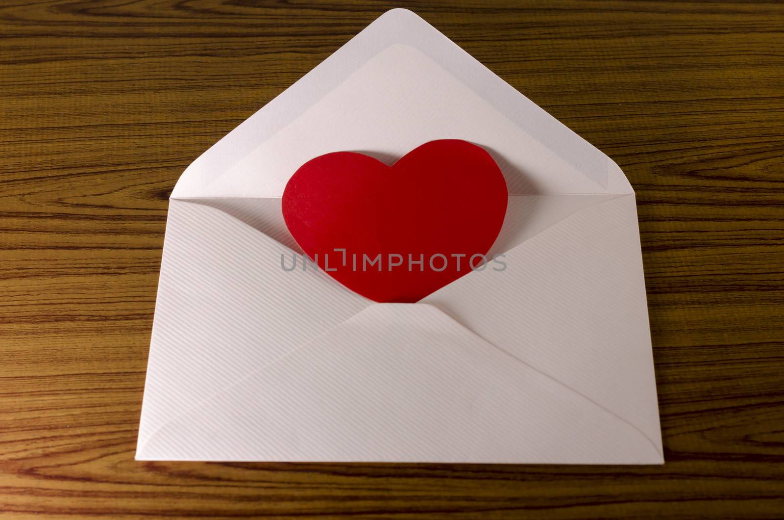 red heart with pink envelope on wooden background