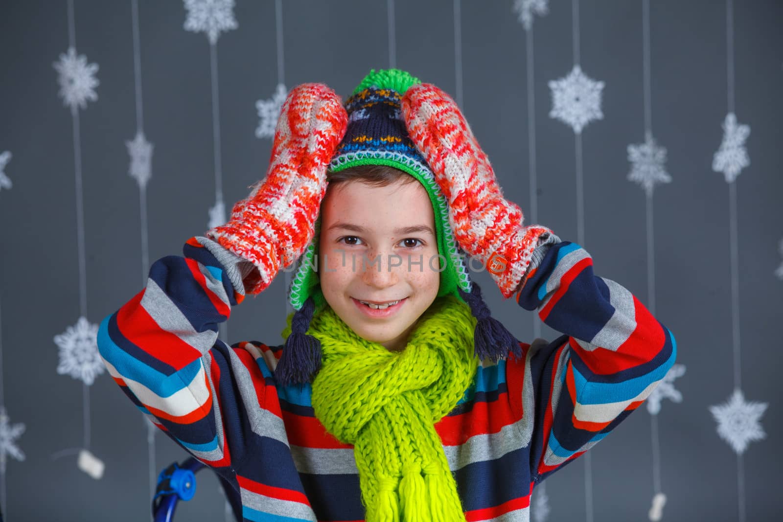 Winter Fashion. Portrait of adorable happy fashion boy in winter hat gloves and sweater in studio.