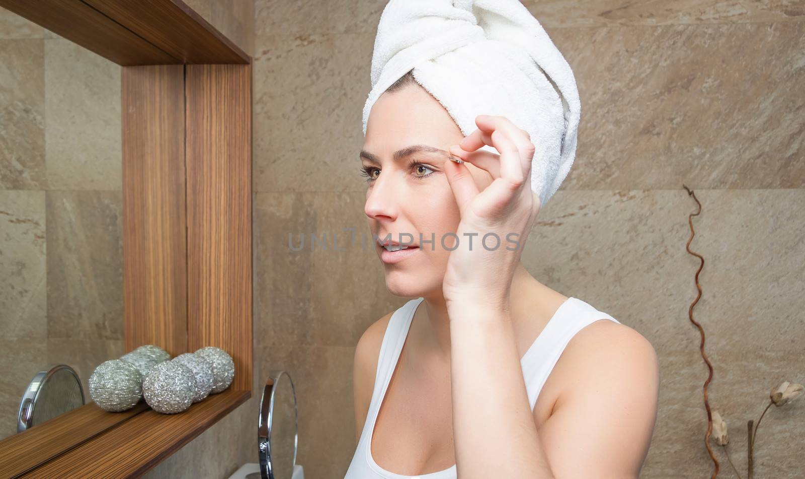 Portrait of girl plucking eyebrows with tweezers by doble.d