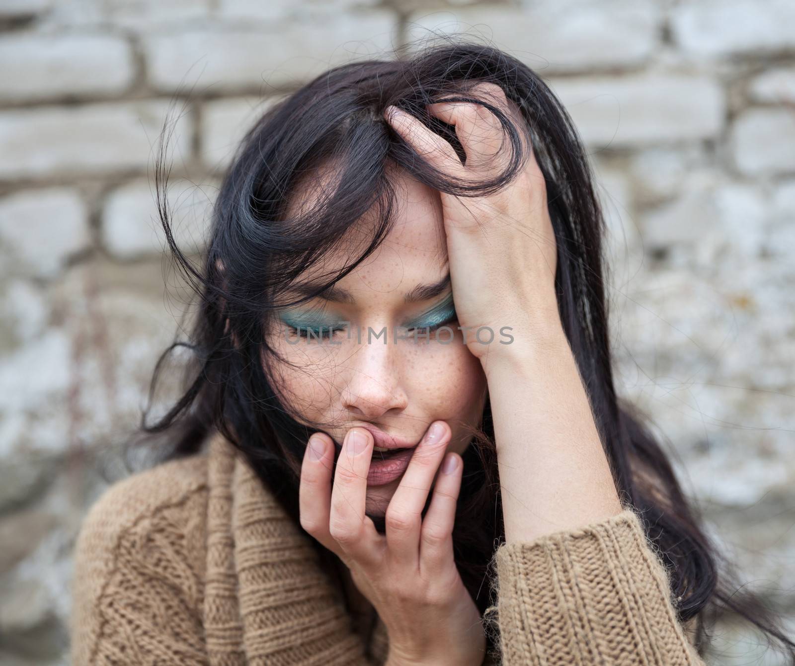 Portrait of a girl with depression against old brick wall