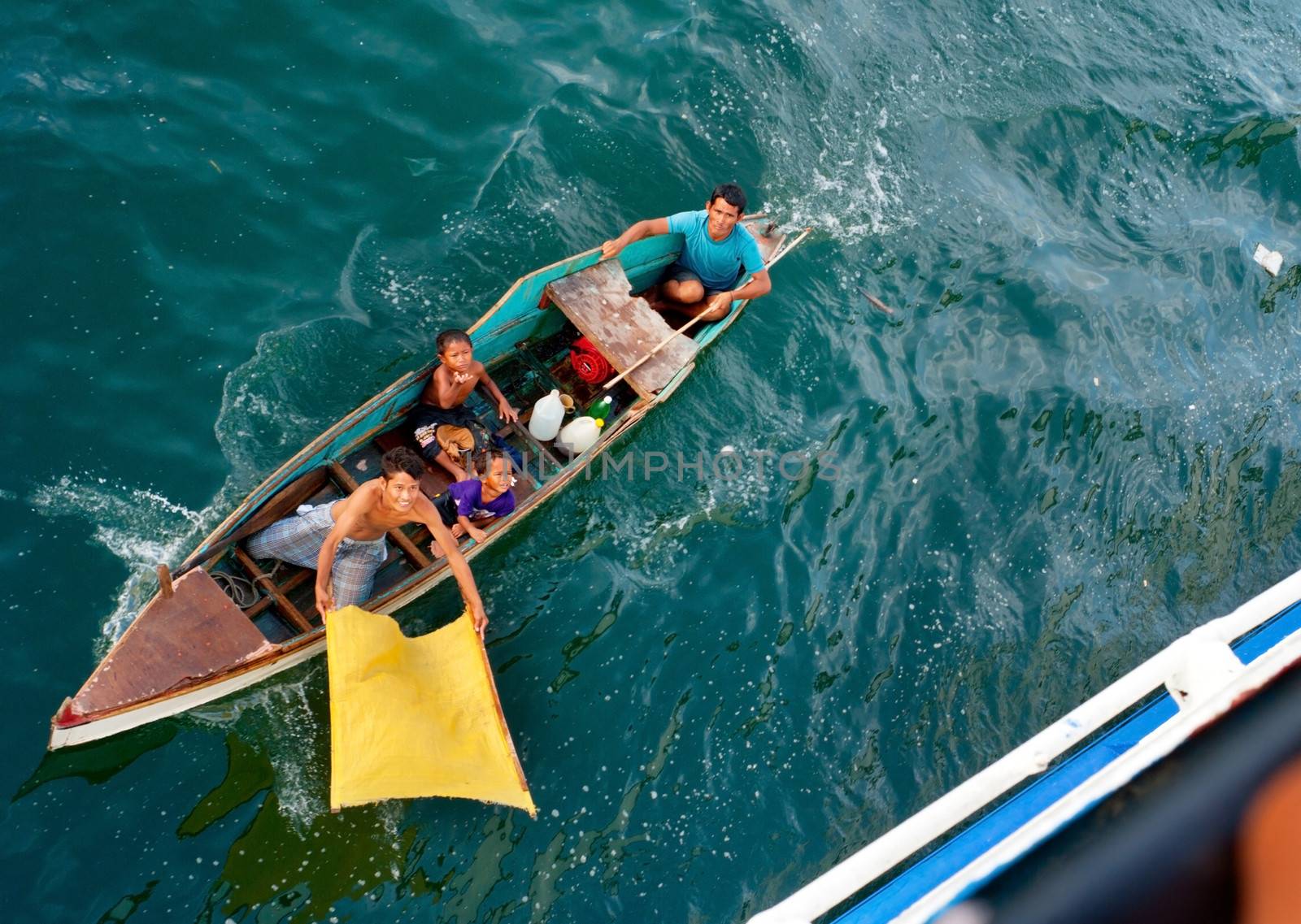 CEBU, PHILIPPINES - MAY 17, 2012: Unidentified beggars asking for a charity in small boat. View from a ship.