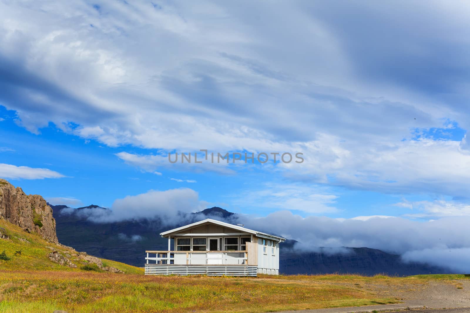 Typical white wooden house against cloudy sky in East Iceland.