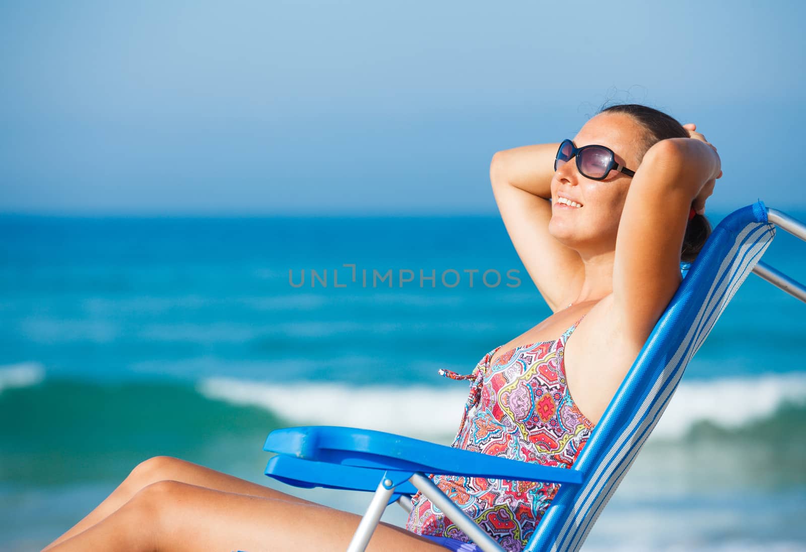 Portrait of young beautiful woman relaxing on deck chair on the beach.