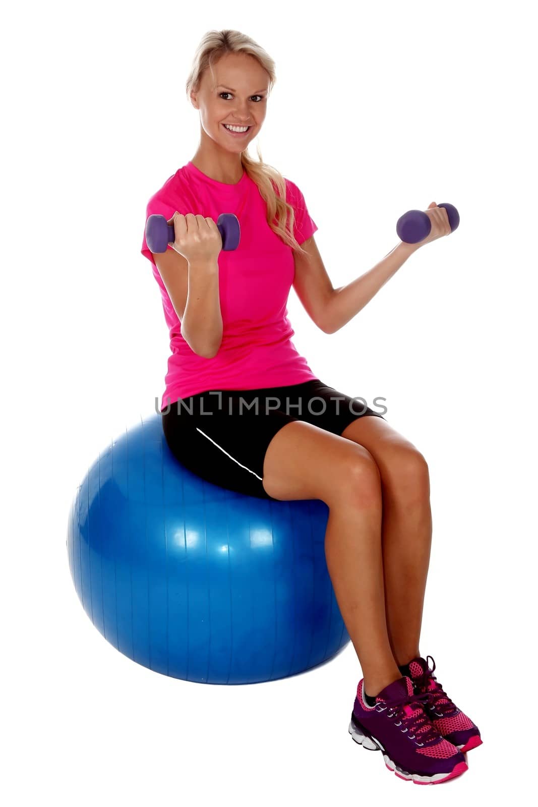 Beautiful woman sitting on exercise ball and lifting weights
