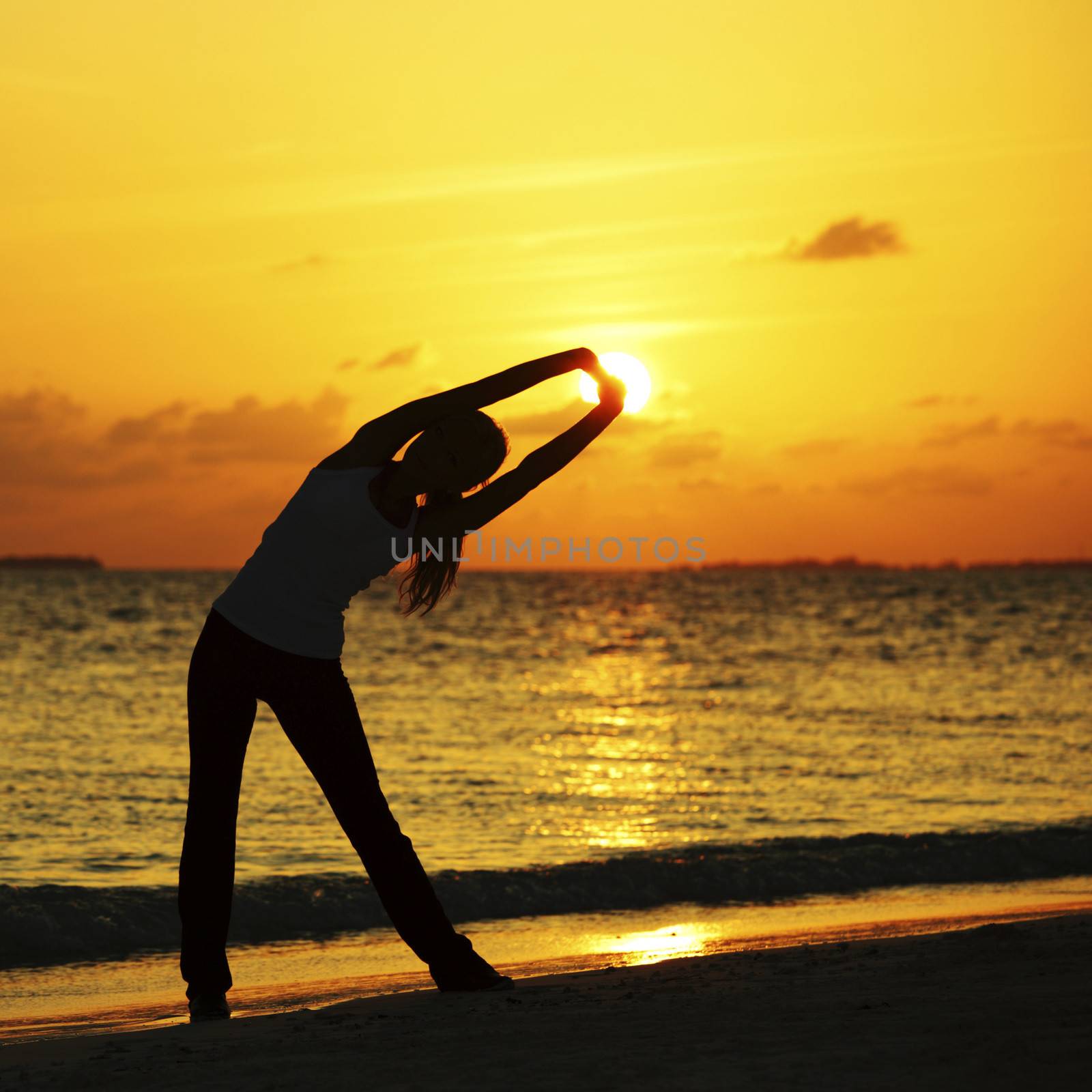 Yoga woman in serene sunset at beach doing stretching workout
