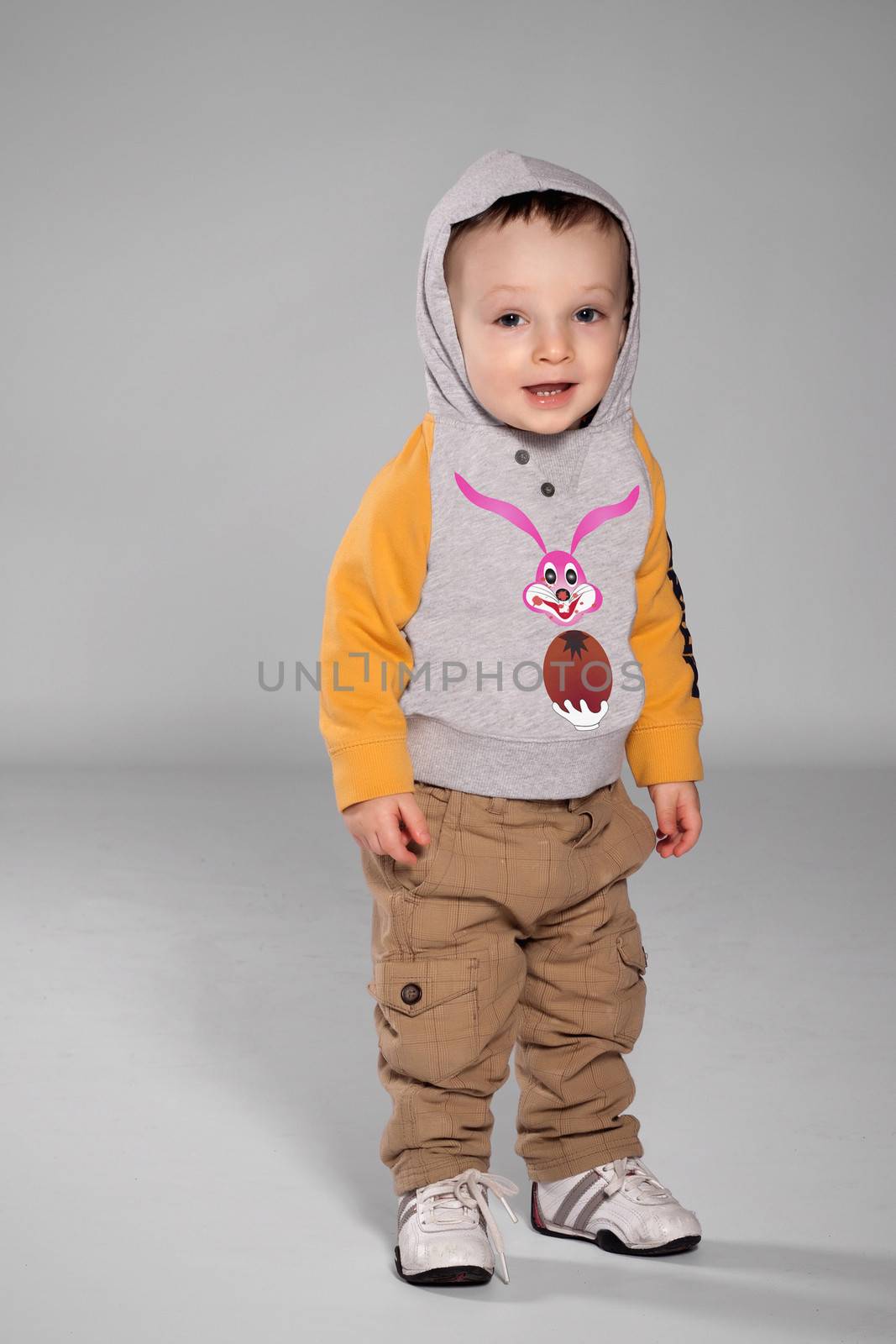 Toddler boy standing in the Easter Bunny sweatshirt with a hood on his head and sneakers