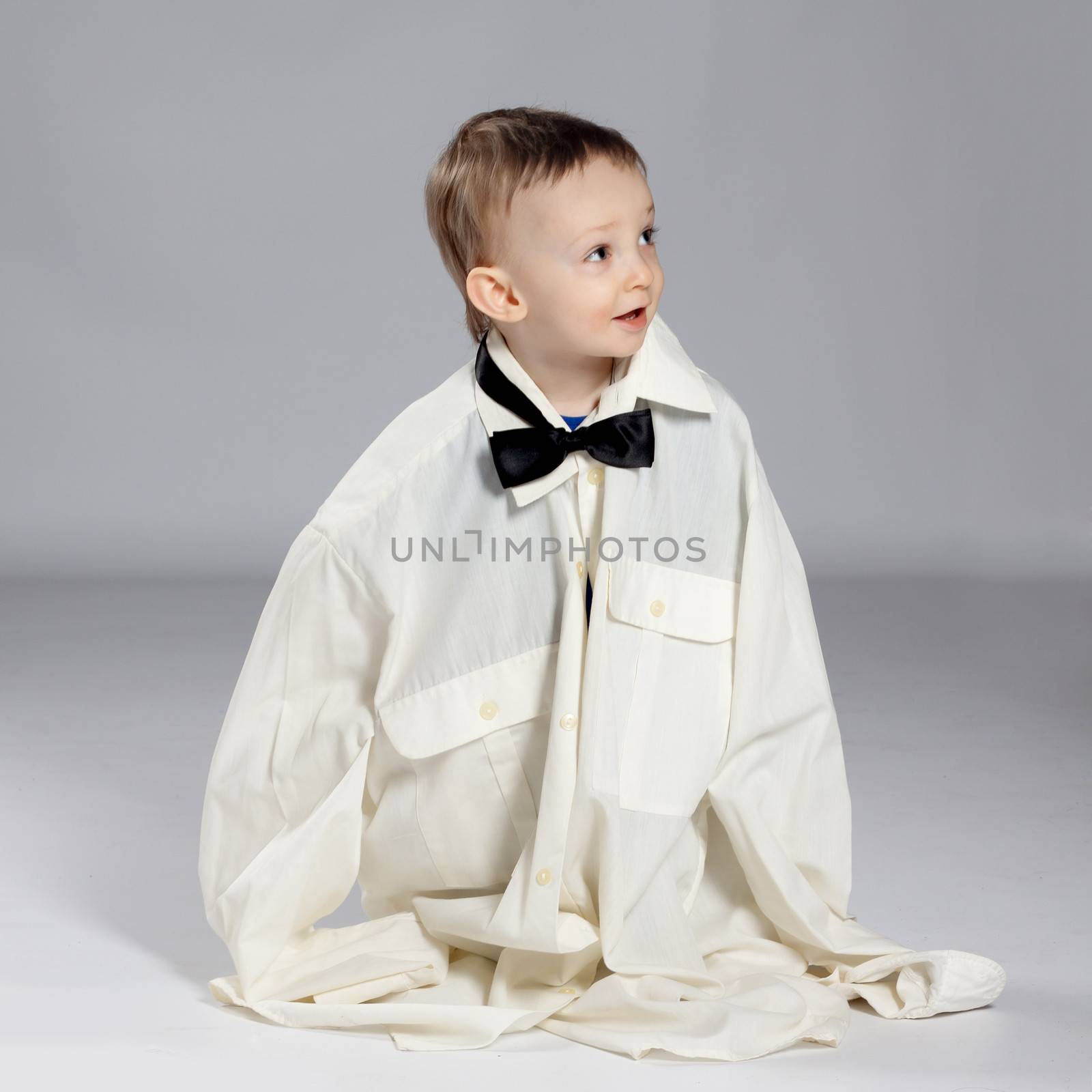 Boy toddler businessman, standing dressed in grown-shirt with bow tie