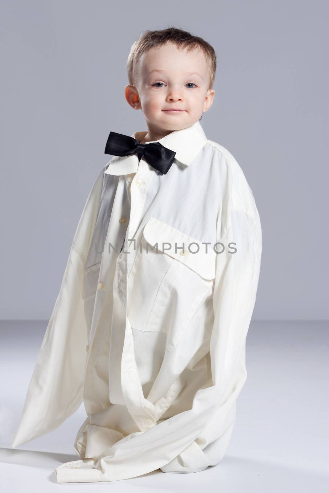 Boy toddler businessman, standing dressed in grown-shirt with bow tie