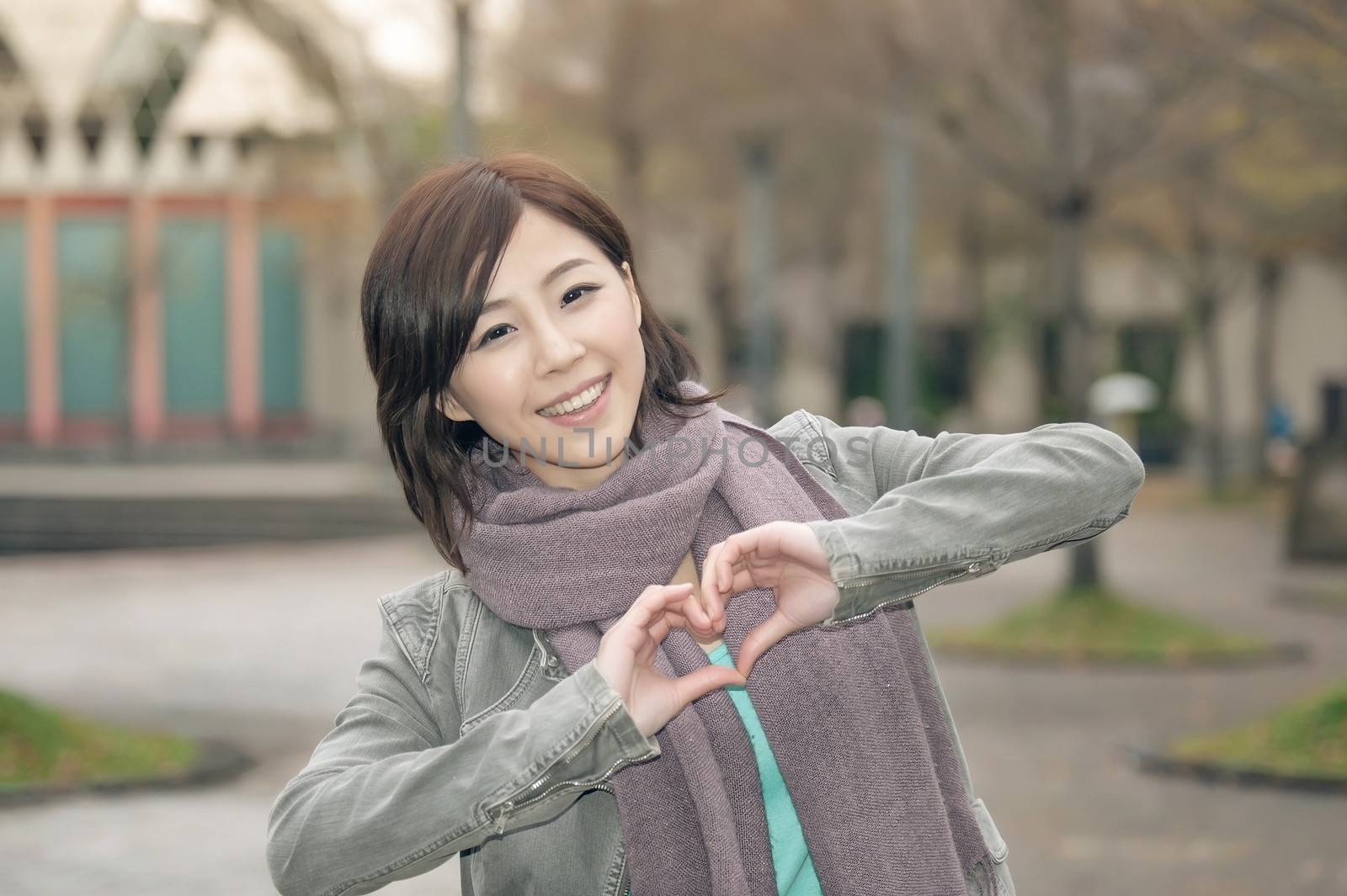 Attractive young woman showing a love shape gesture in the park, Taipei, Taiwan.