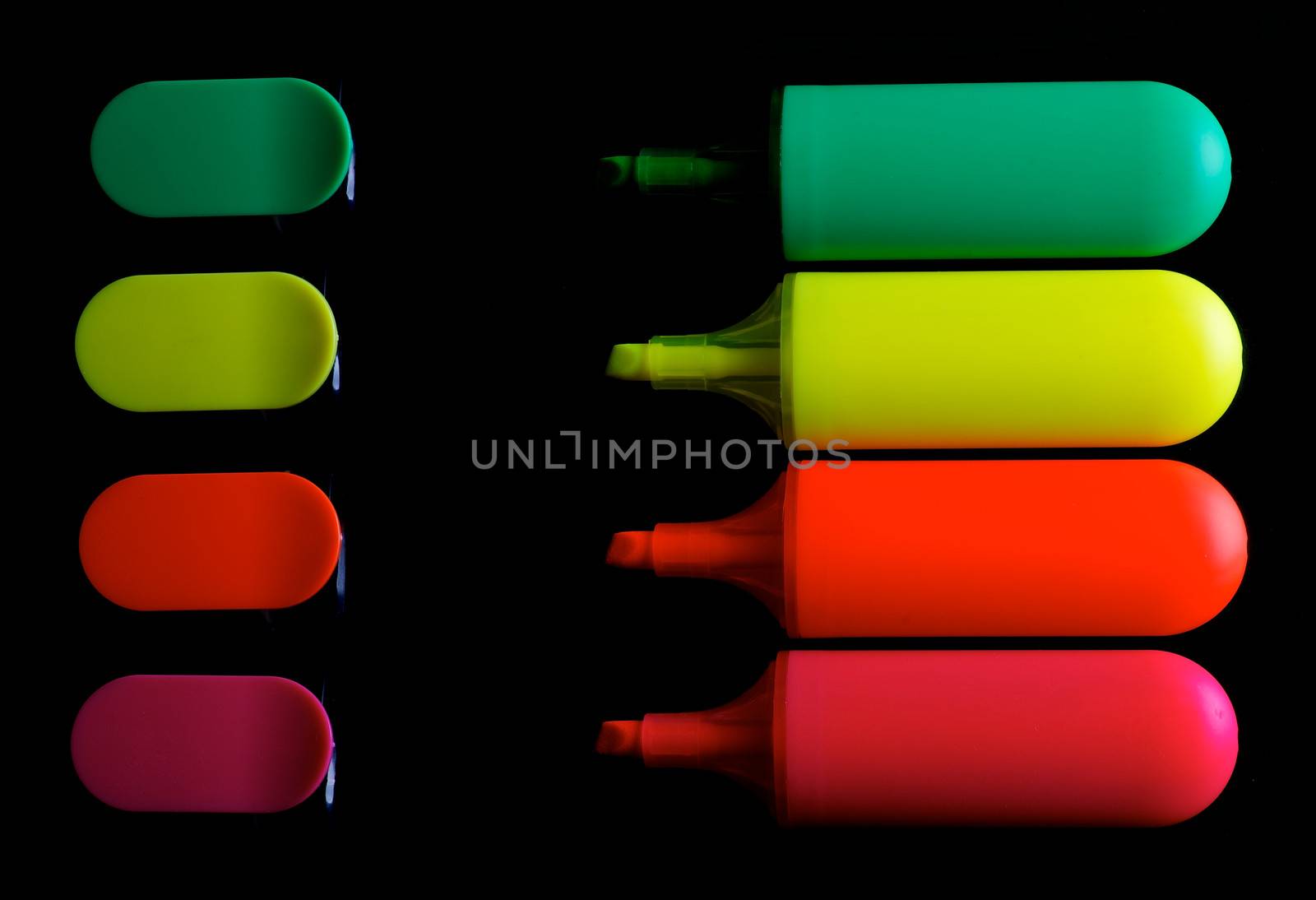 Red, Orange, Yellow and Green Fluorescent Highlighter Pens with Caps In a Row isolated on black background