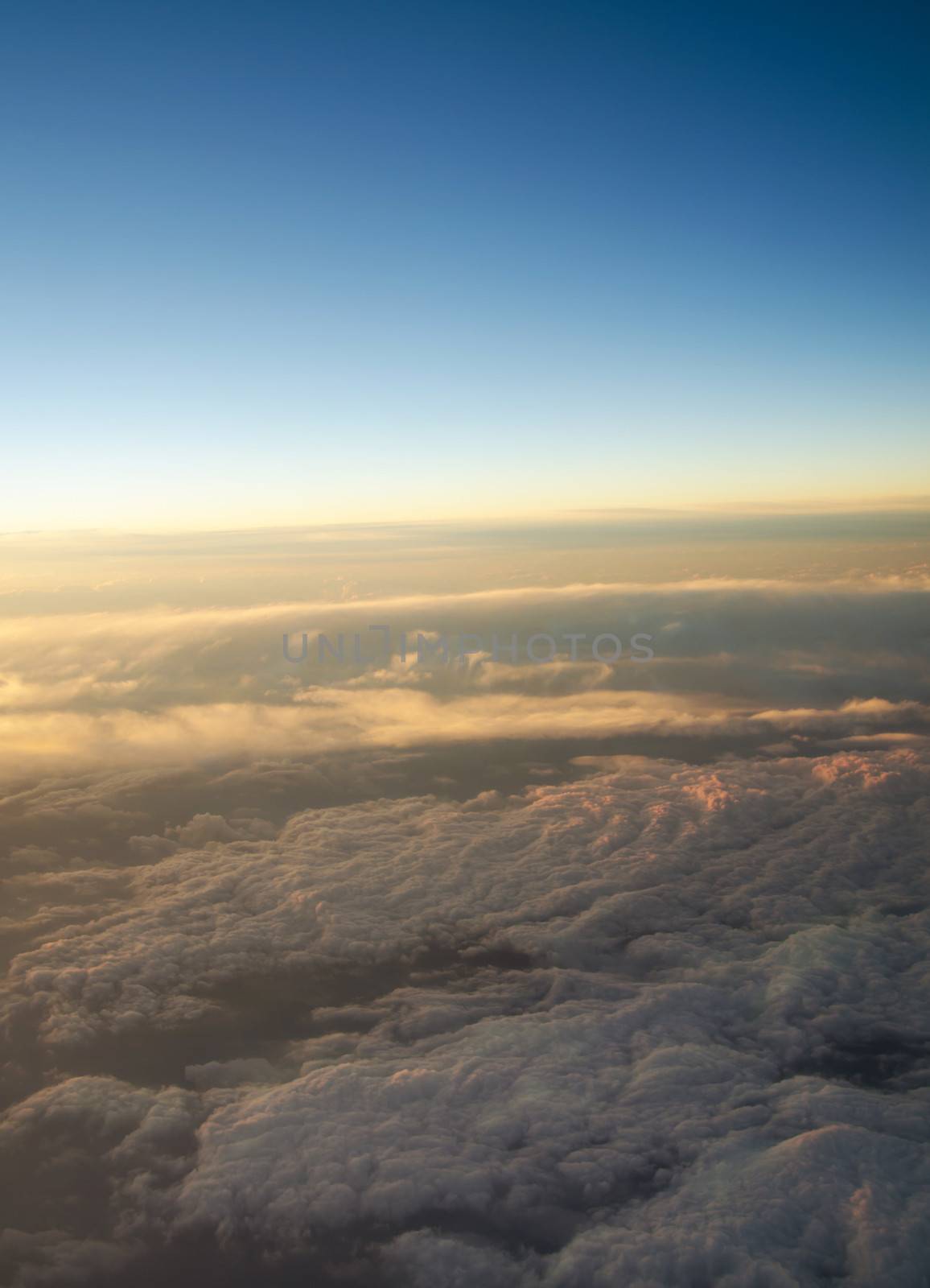 Aerial view of a cloudy sunrise while flying above the clouds. 